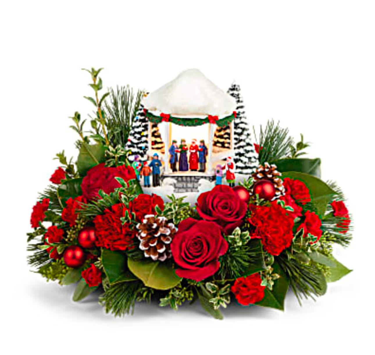 Christmas floral arrangement with red roses and a miniature holiday village centerpiece