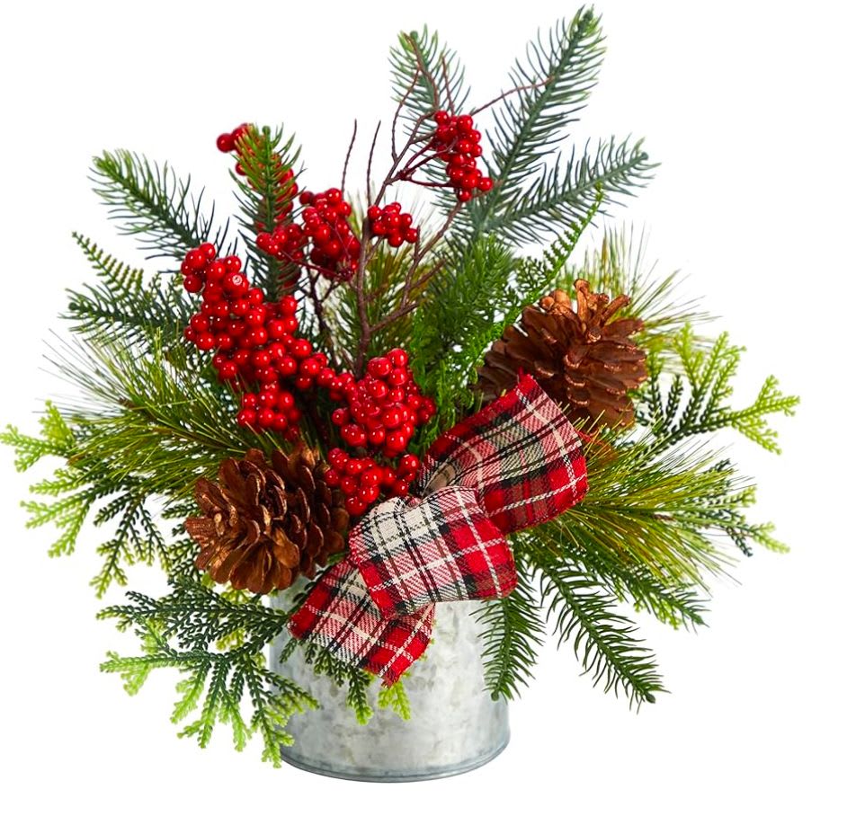 Holiday arrangement with pine branches, red berries, pinecones, and plaid ribbon in a metal bucket