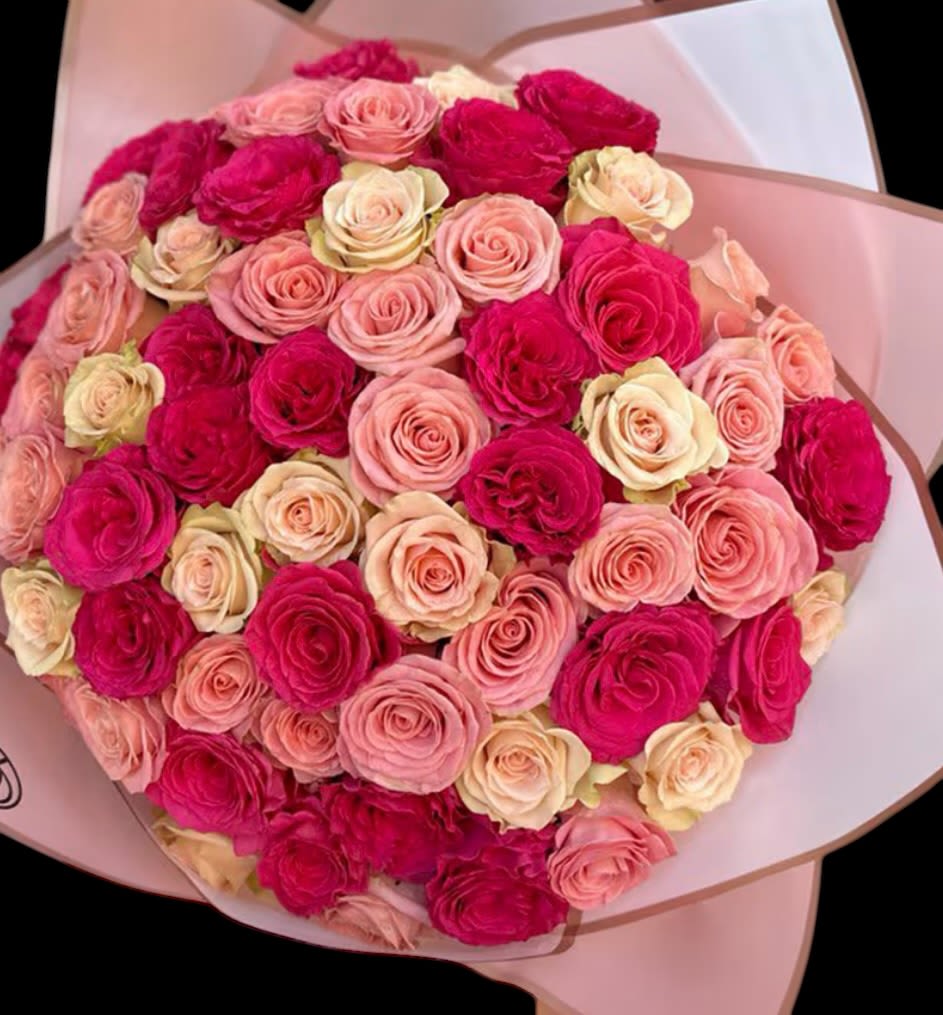 Bouquet of pink and cream roses wrapped in pale paper