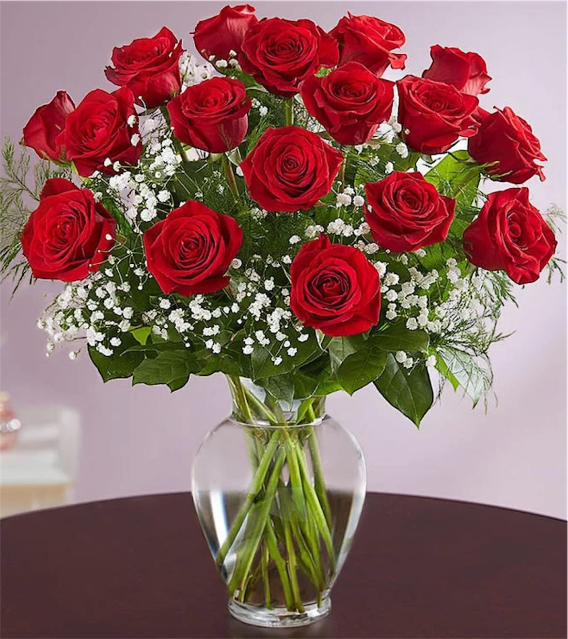 Red roses arranged in a clear glass vase with white baby's breath