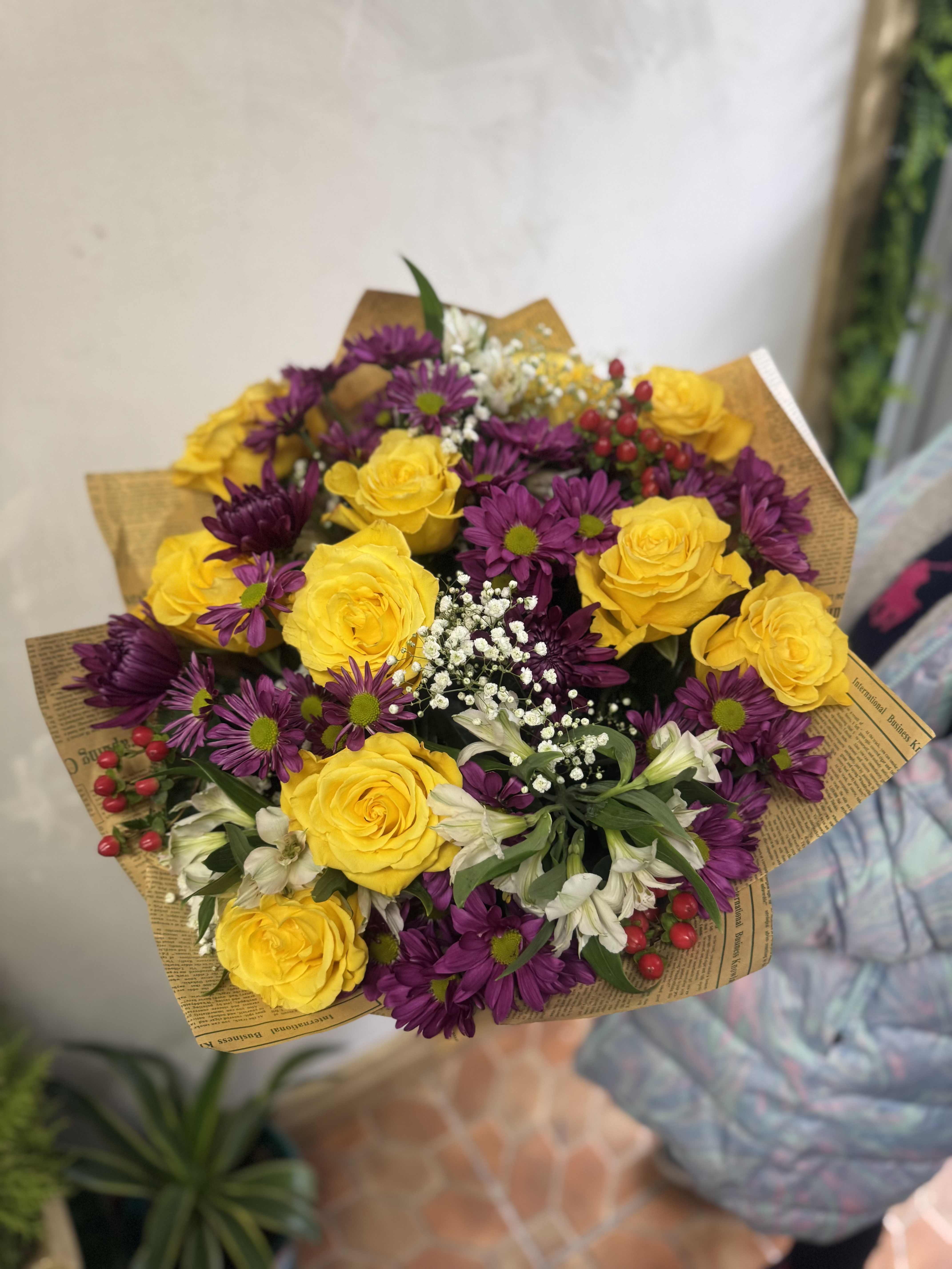 Bouquet of yellow roses and purple daisies with white filler flowers