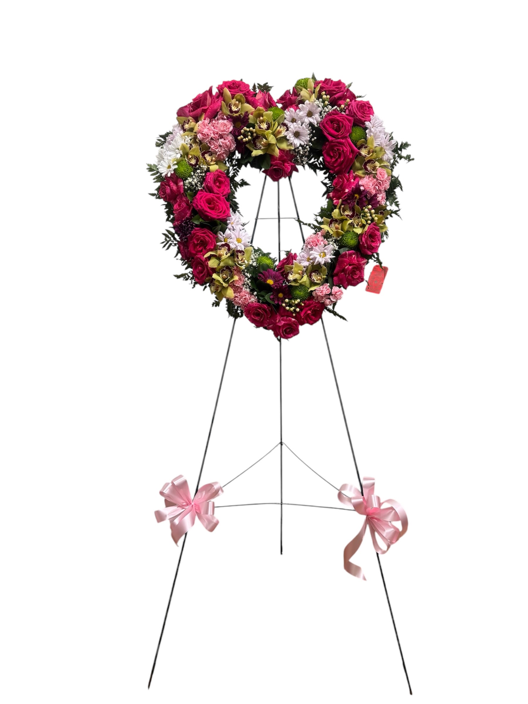 Heart-shaped floral wreath on a standing easel with pink ribbons