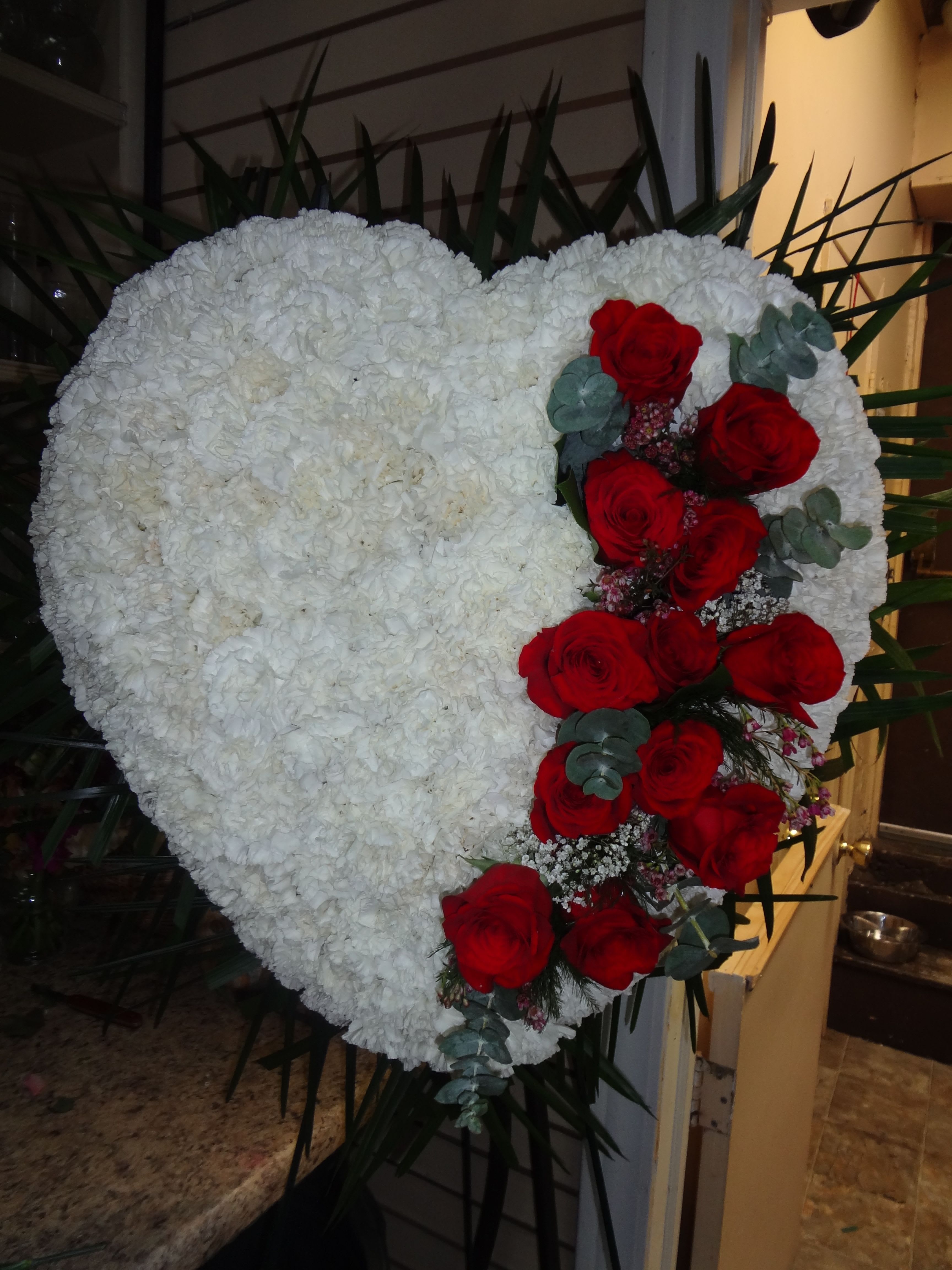 Heart-shaped white floral wreath with red roses