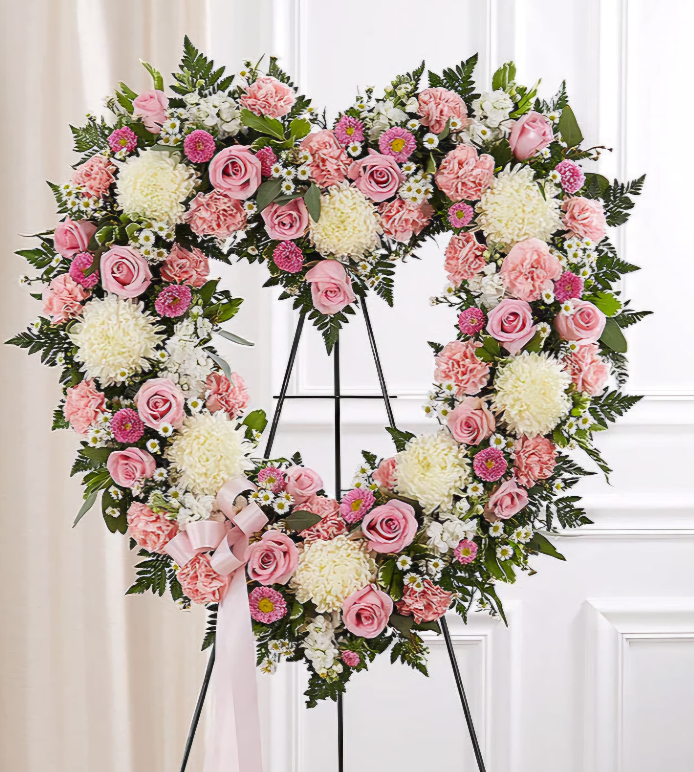 Heart-shaped floral wreath with pink and white flowers on a stand
