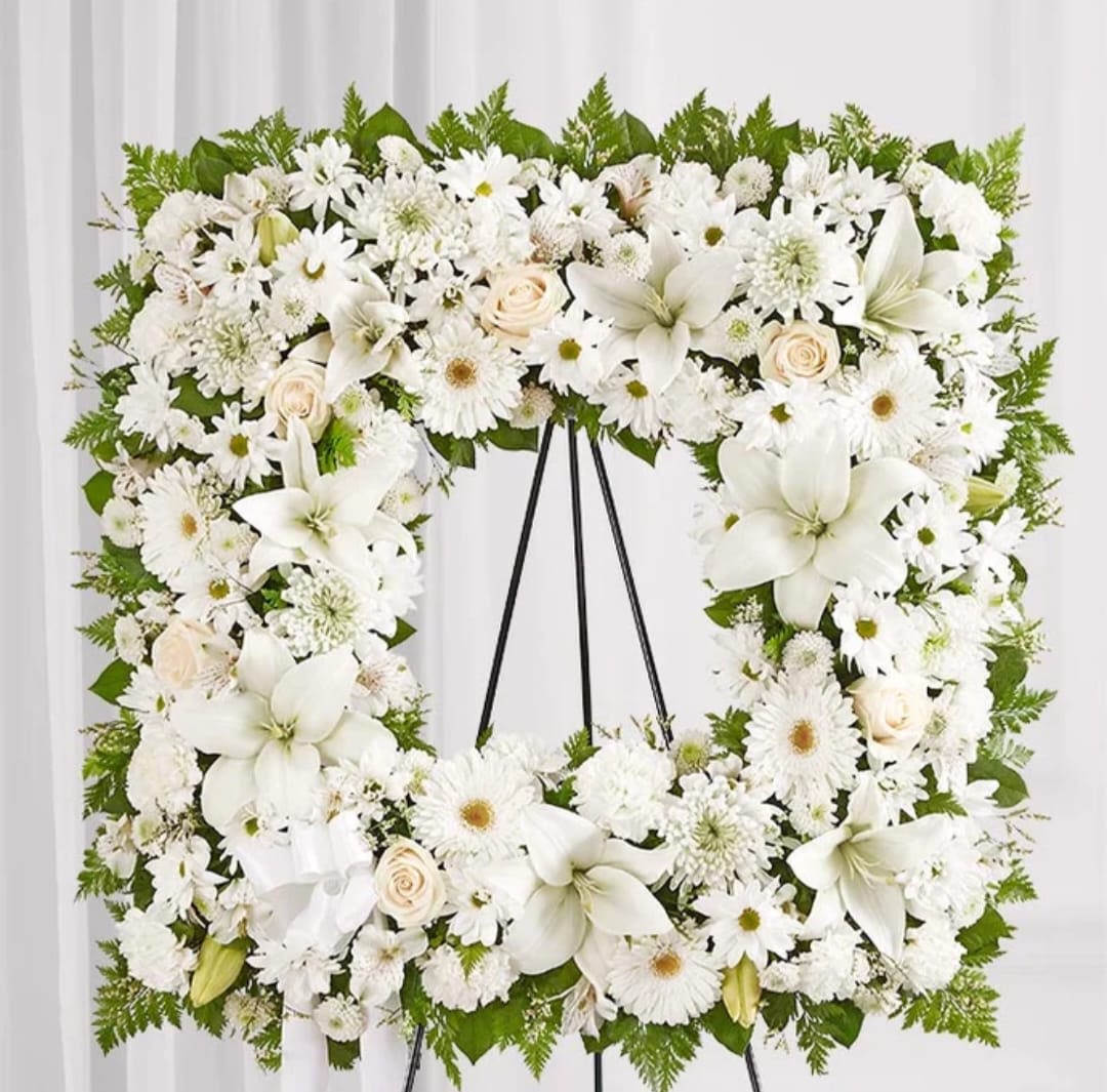 White floral funeral wreath on a black easel