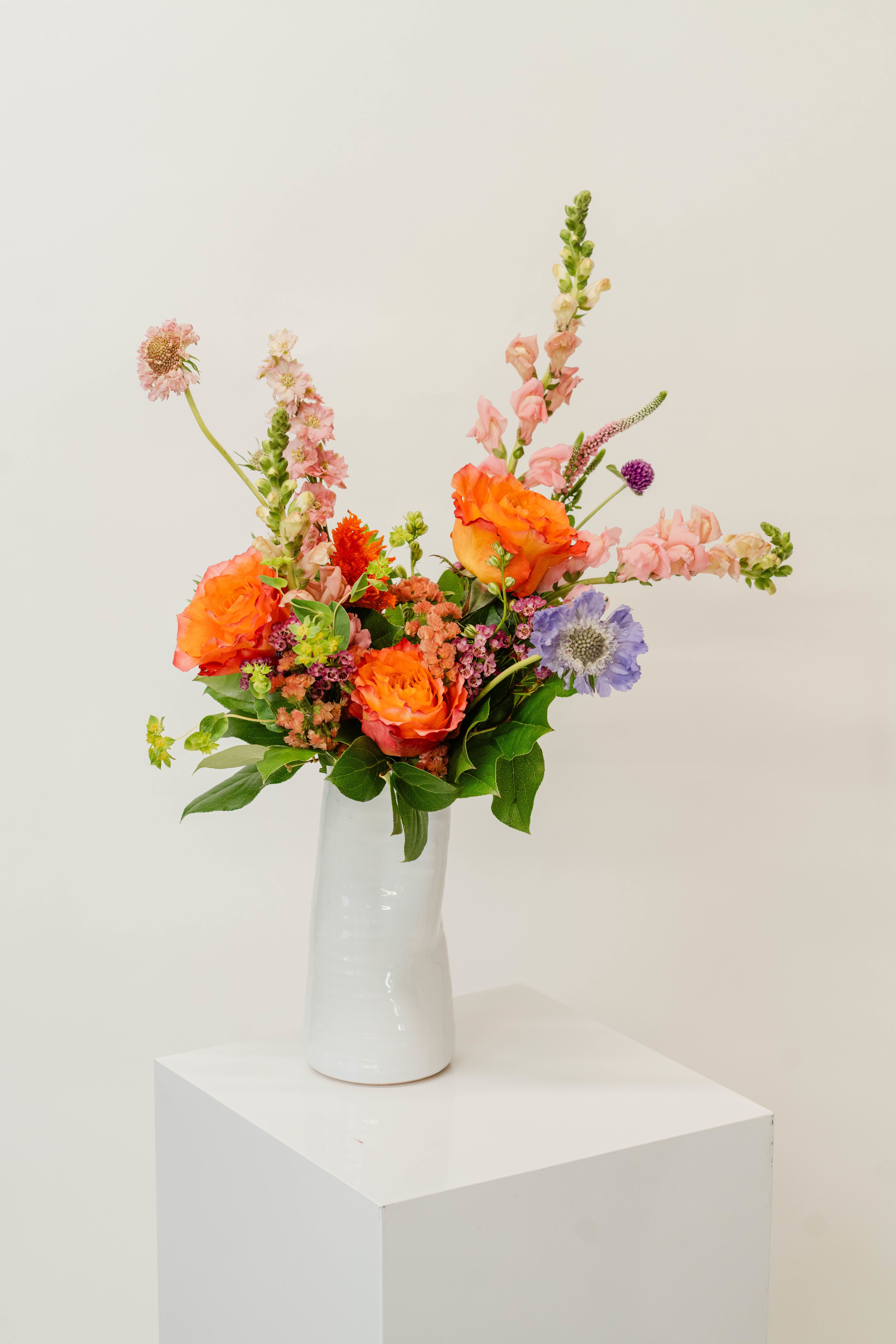 Colorful mixed flower arrangement in a white vase