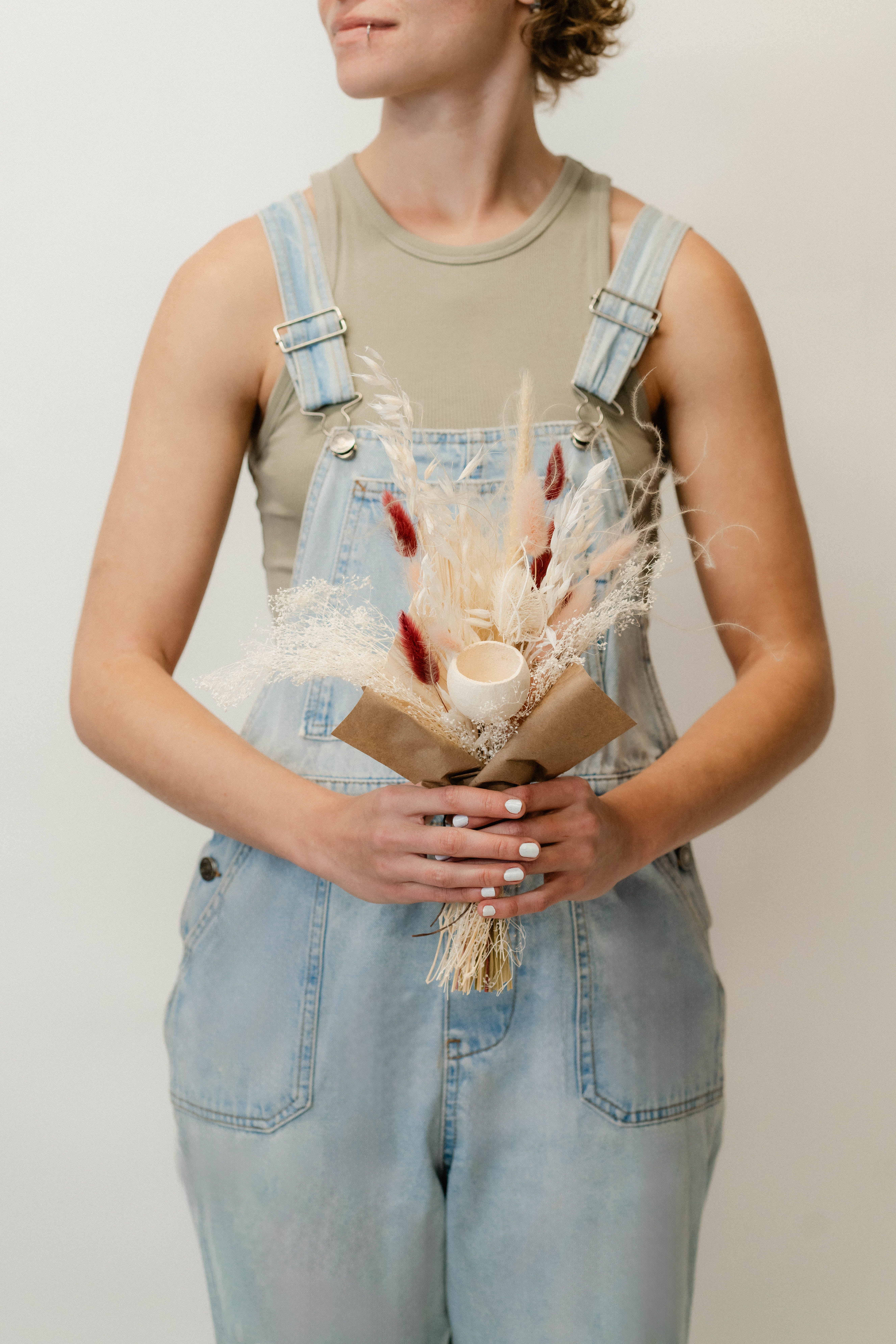 Person holding a small dried bouquet with a candle