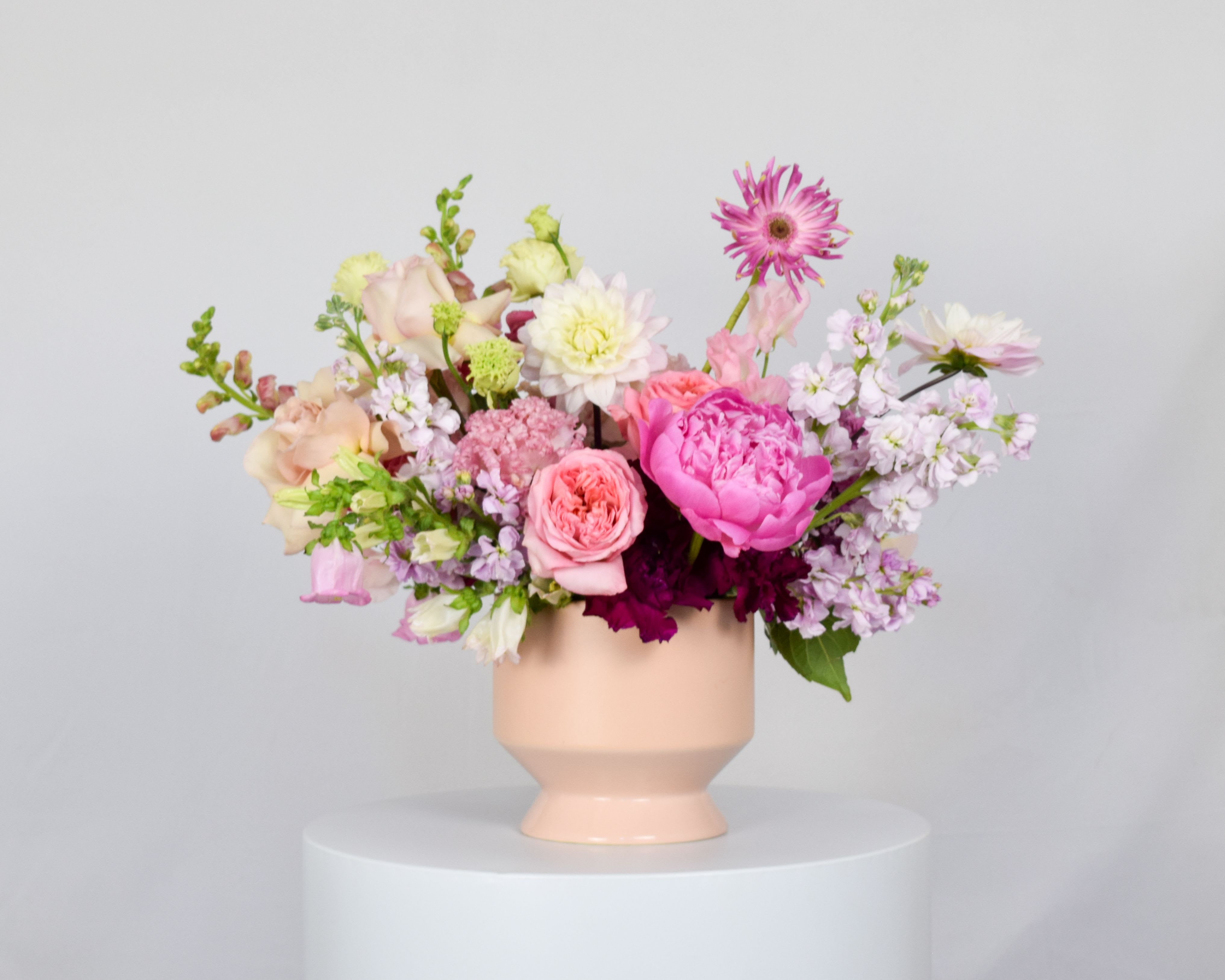 Pink and white mixed flower arrangement in a peach vase
