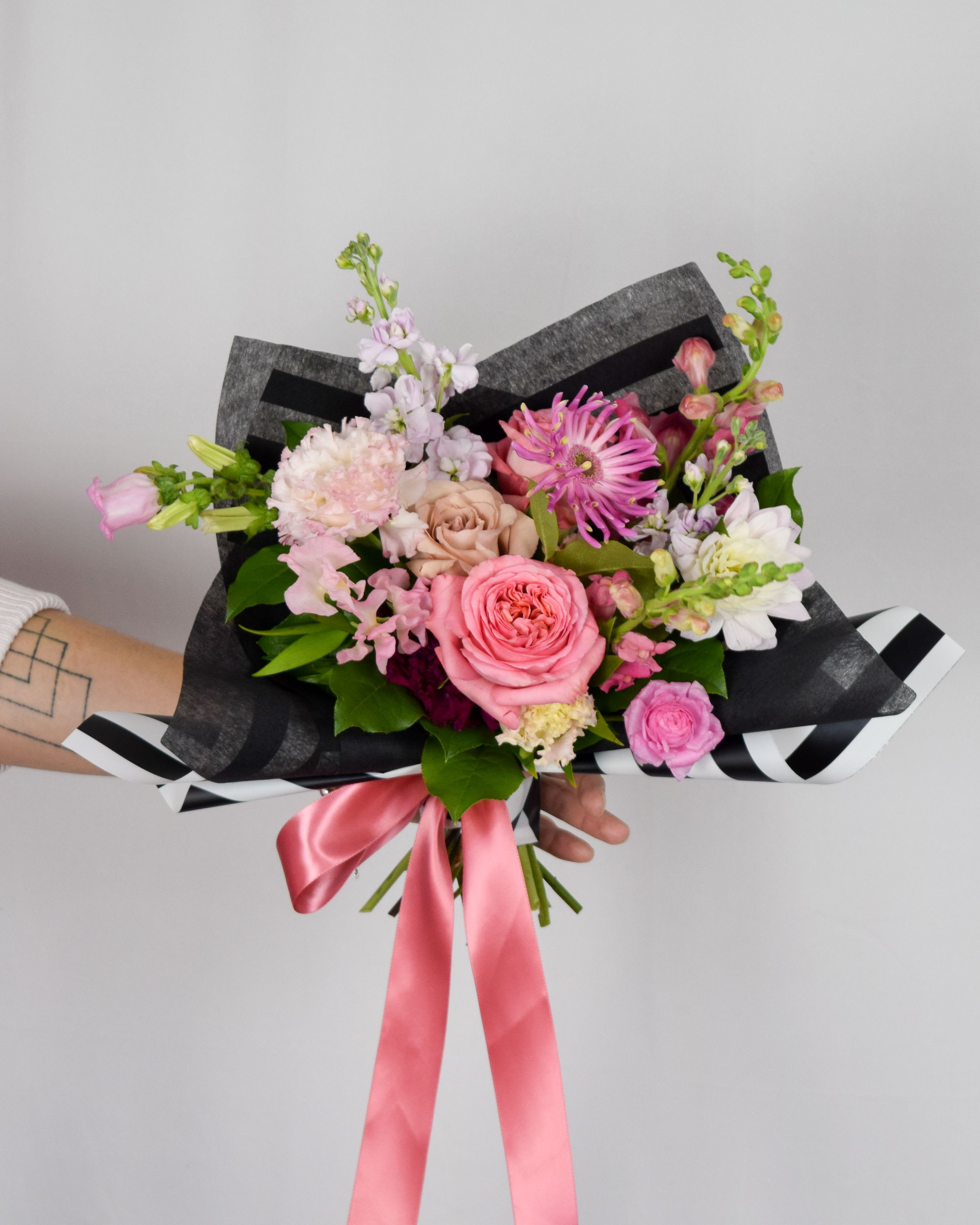 Hand-tied bouquet of pink and white flowers with a pink ribbon