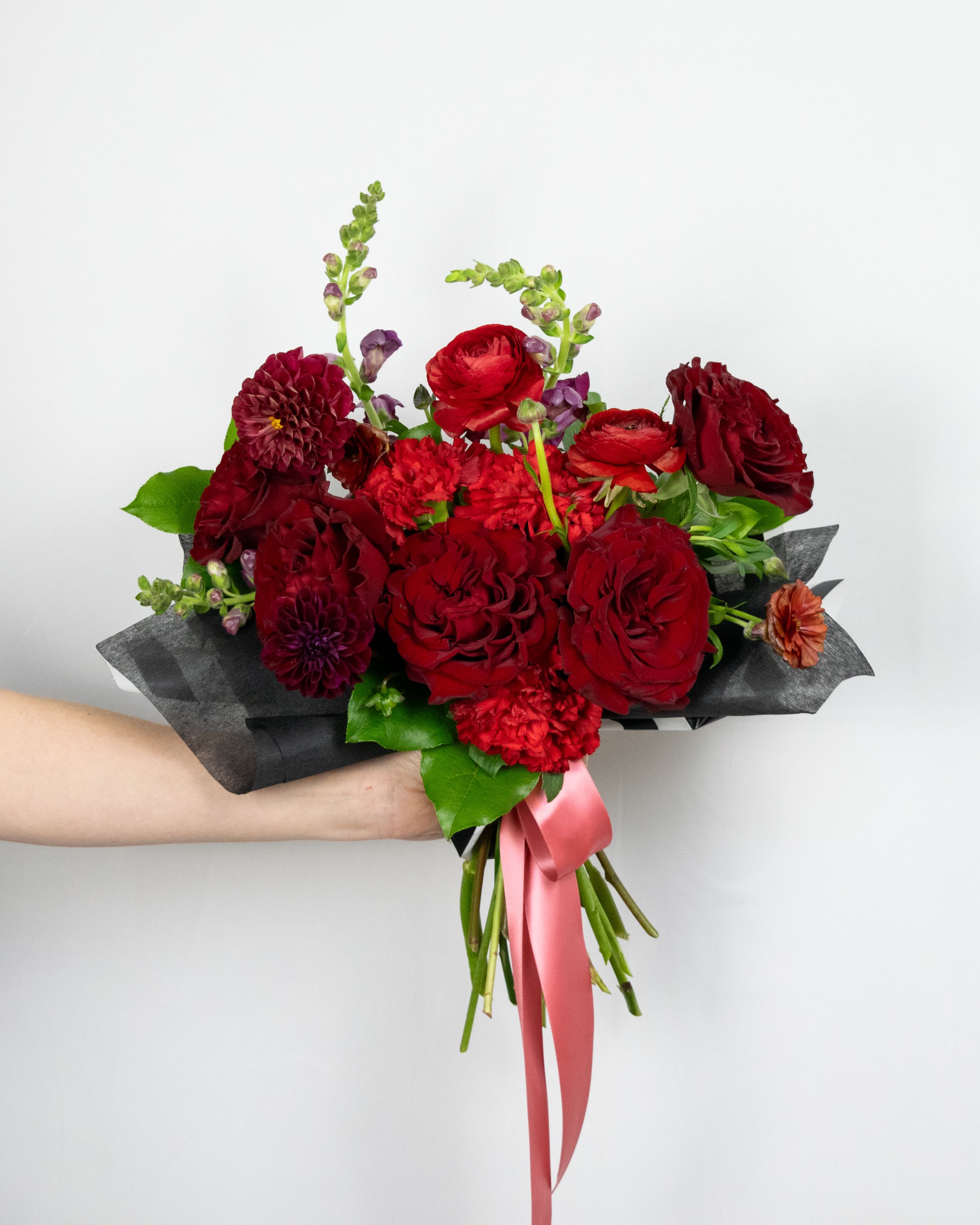 Hand-tied bouquet of red flowers with a pink ribbon