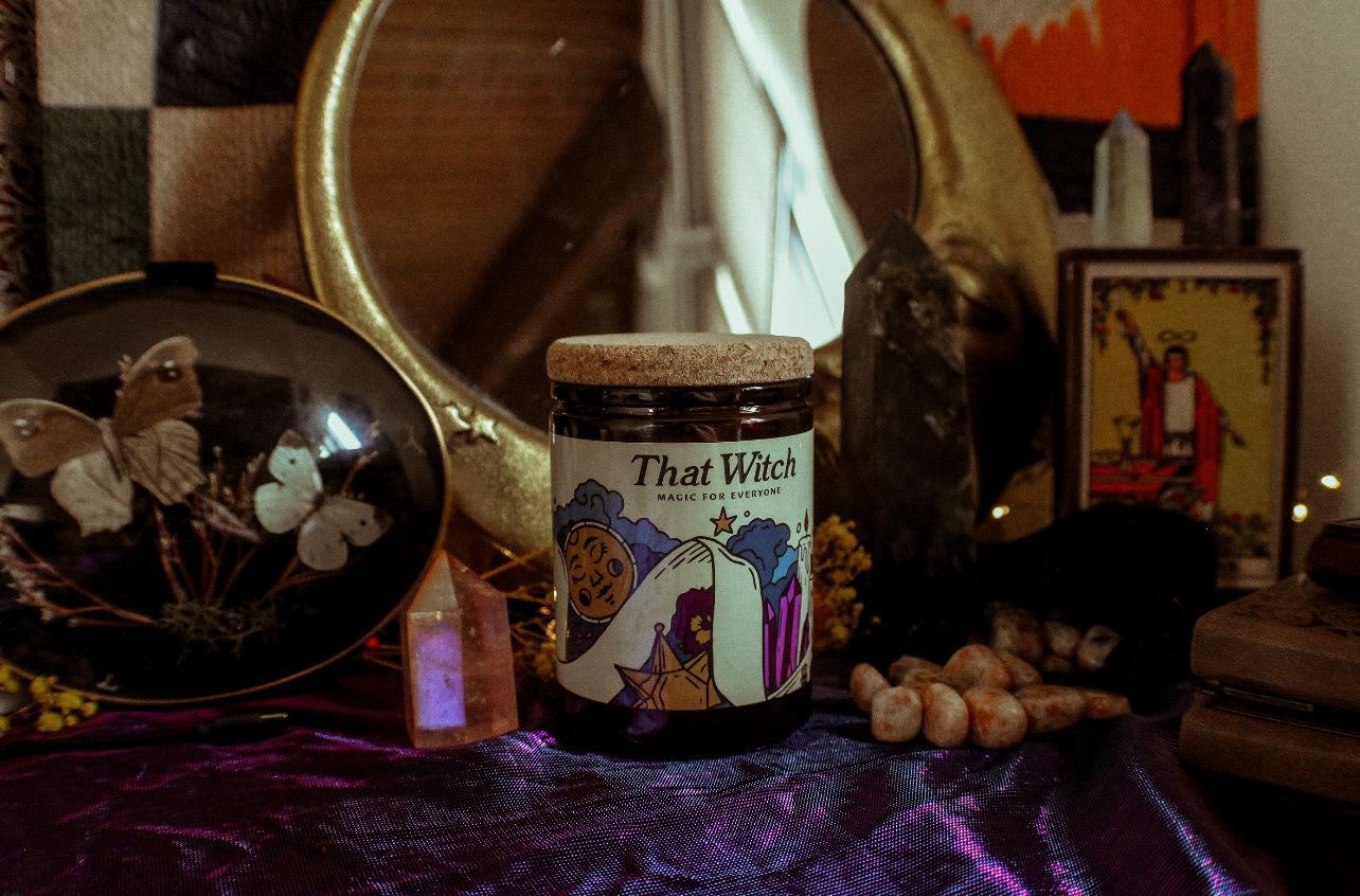 Jar candle labeled "That Witch" on a dark altar-like display