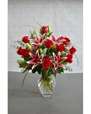 Red roses and pink lilies arranged in a clear glass vase
