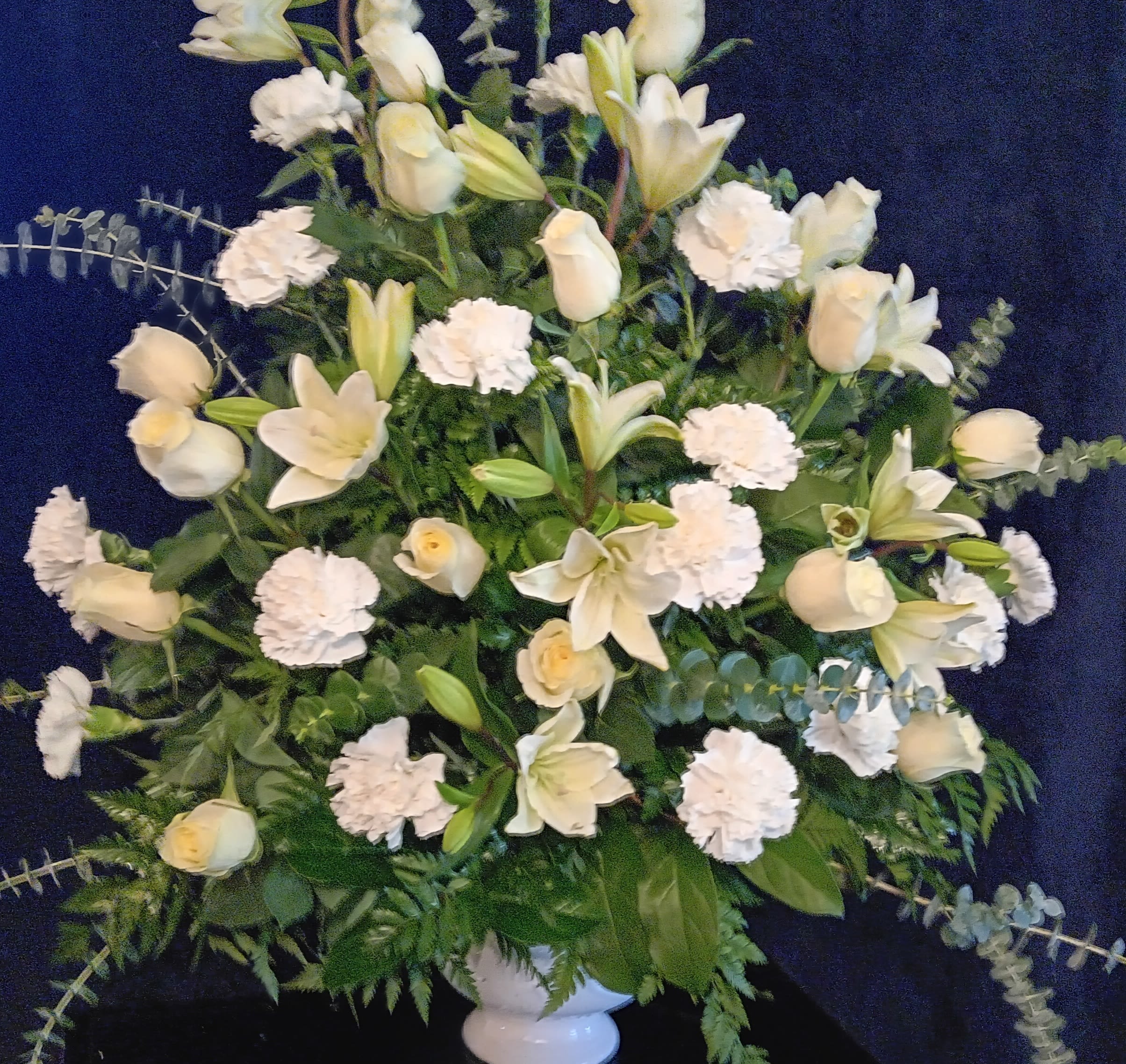 White floral arrangement with lilies, roses, and carnations in a vase