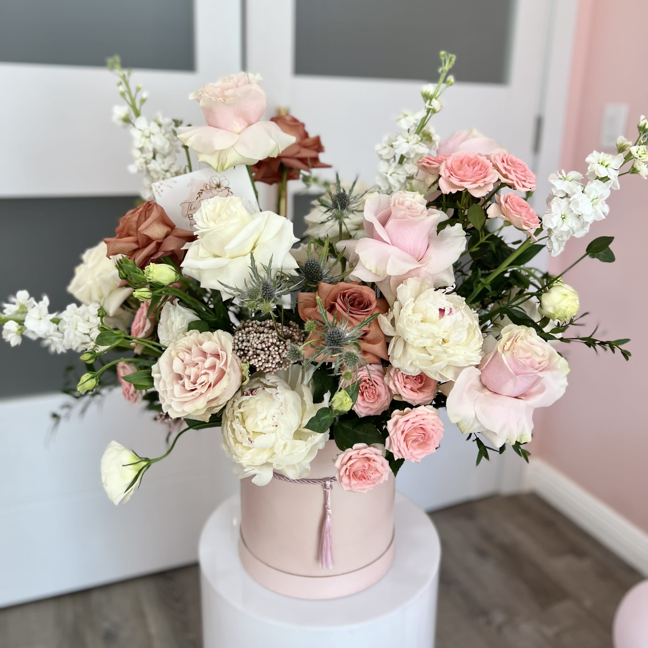 Pink and white roses arranged in a round hatbox