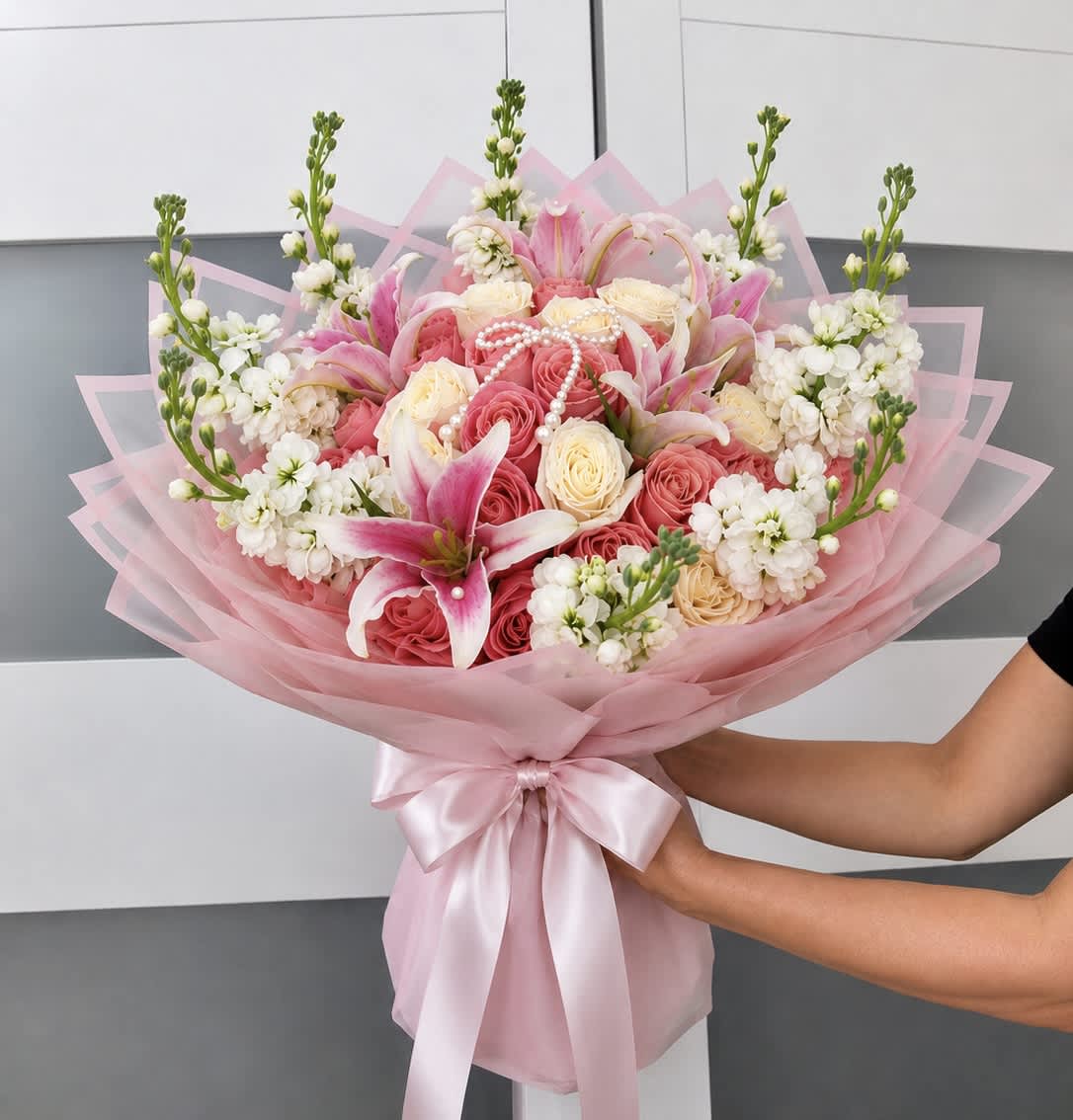 Pink and white bouquet of roses and lilies wrapped in pink paper
