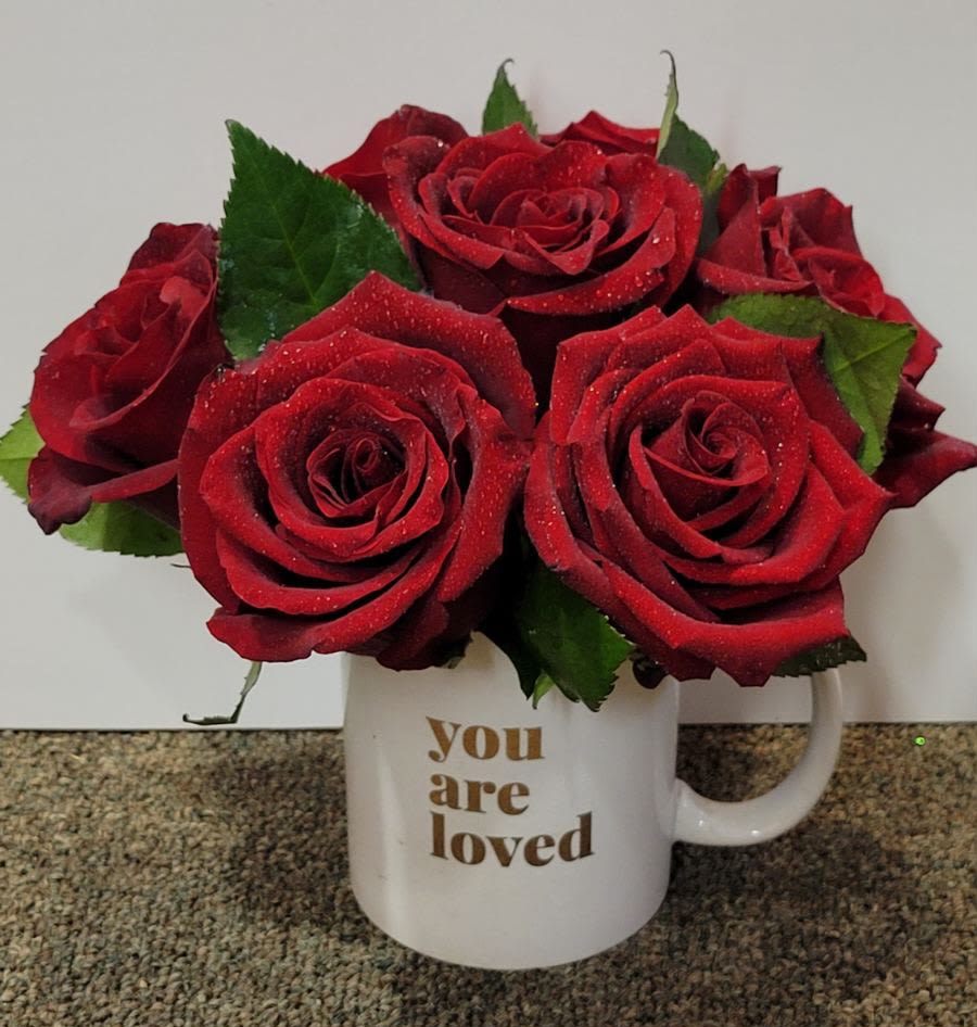 Red roses arranged in a white mug with "you are loved" text
