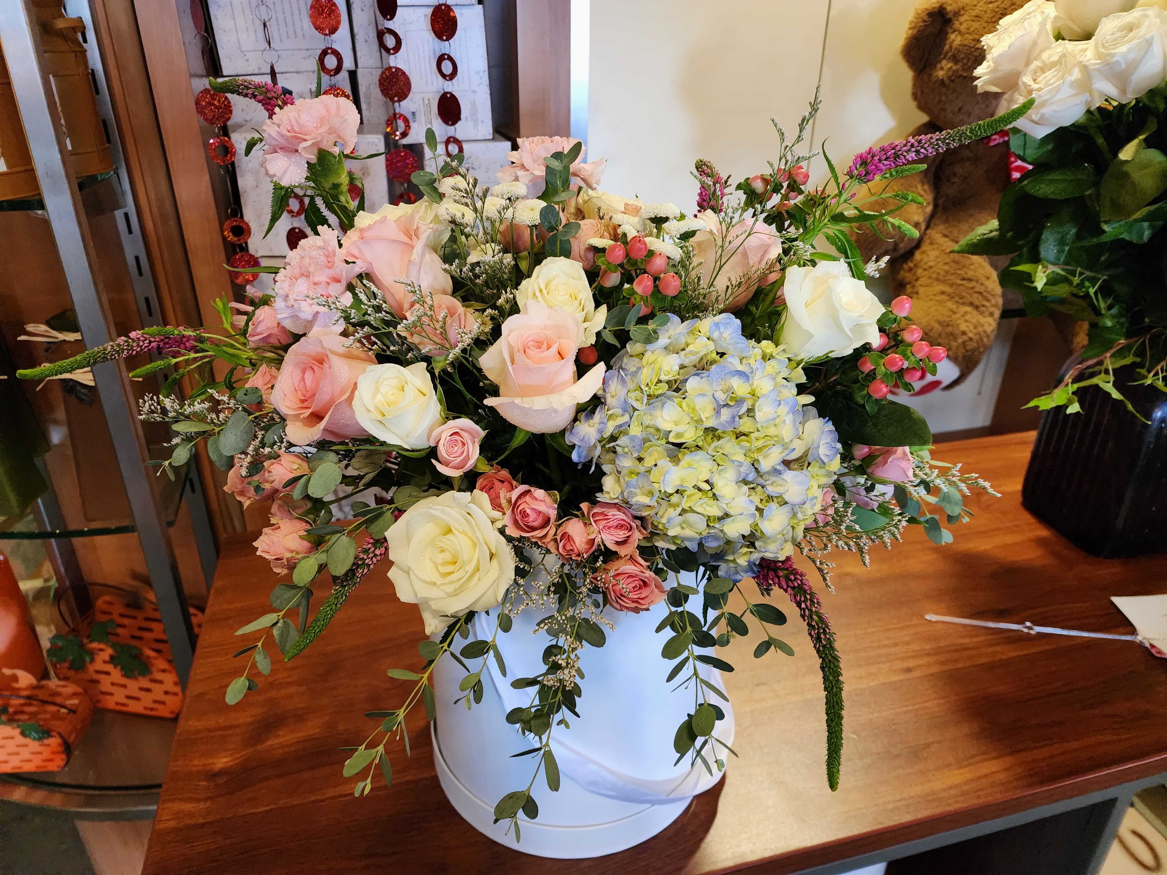 Mixed bouquet of pink and white roses with blue hydrangea in a white vase
