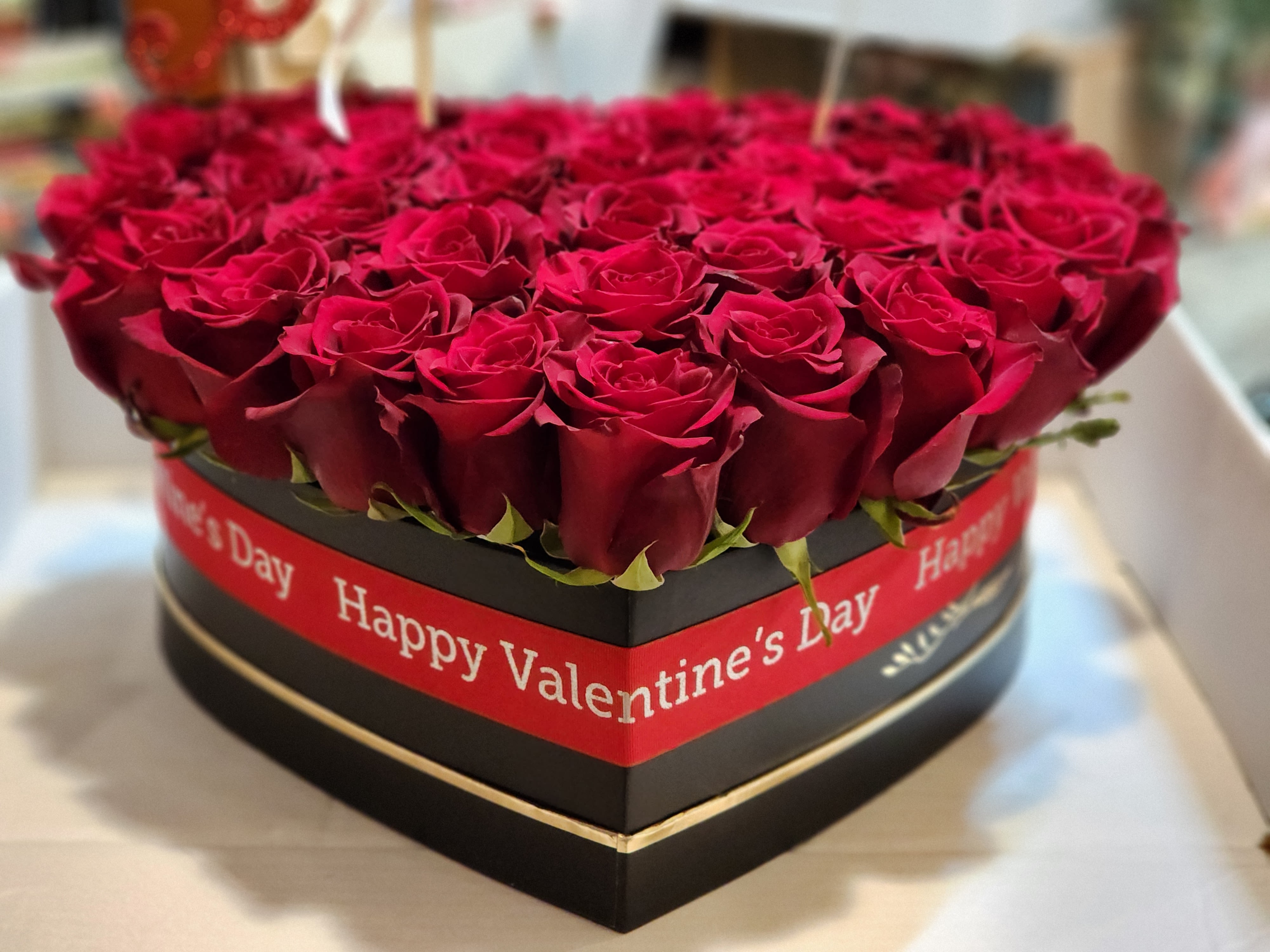 Heart-shaped box of red roses with a Valentine’s Day ribbon