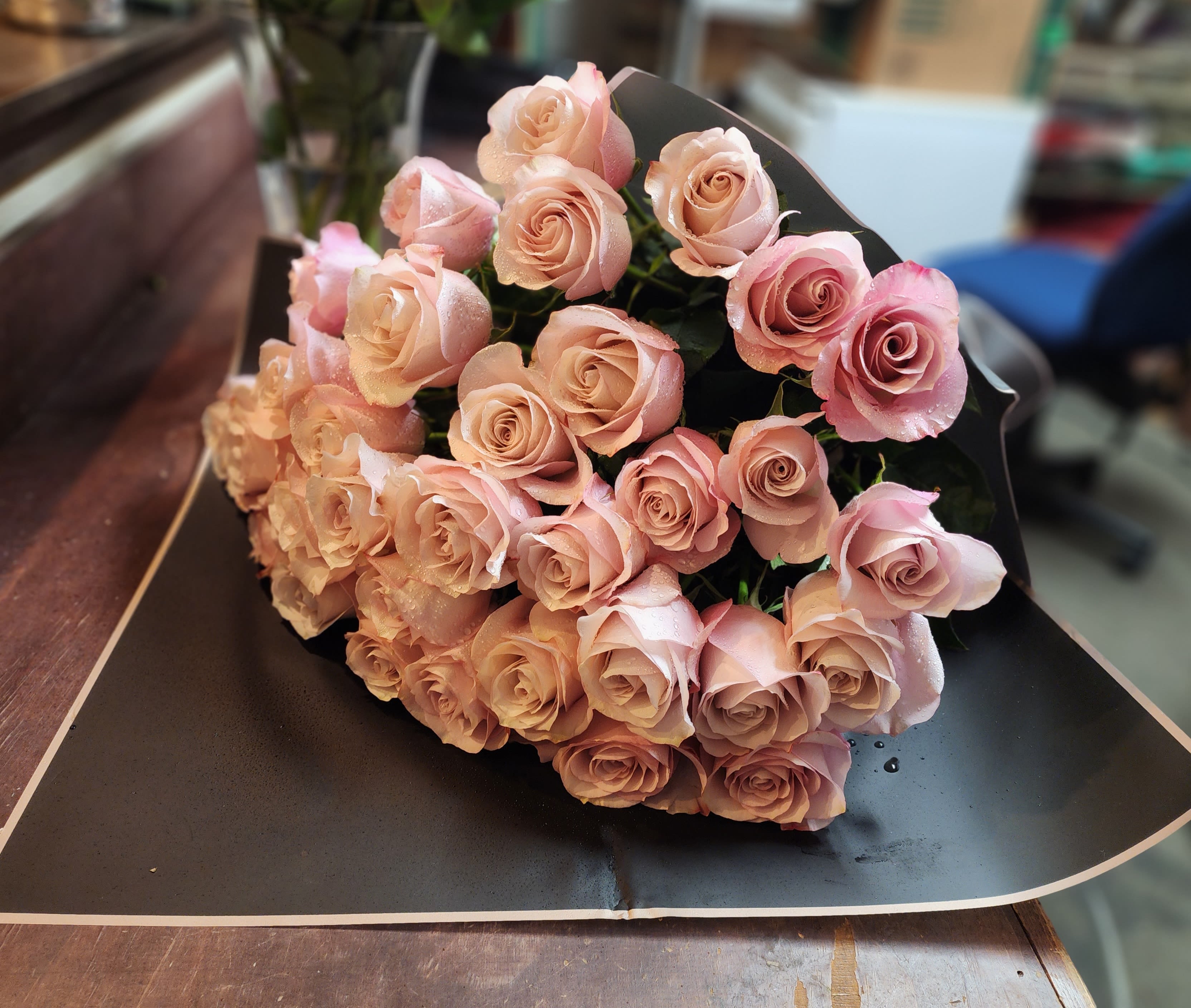 Bouquet of pale pink roses wrapped in black paper