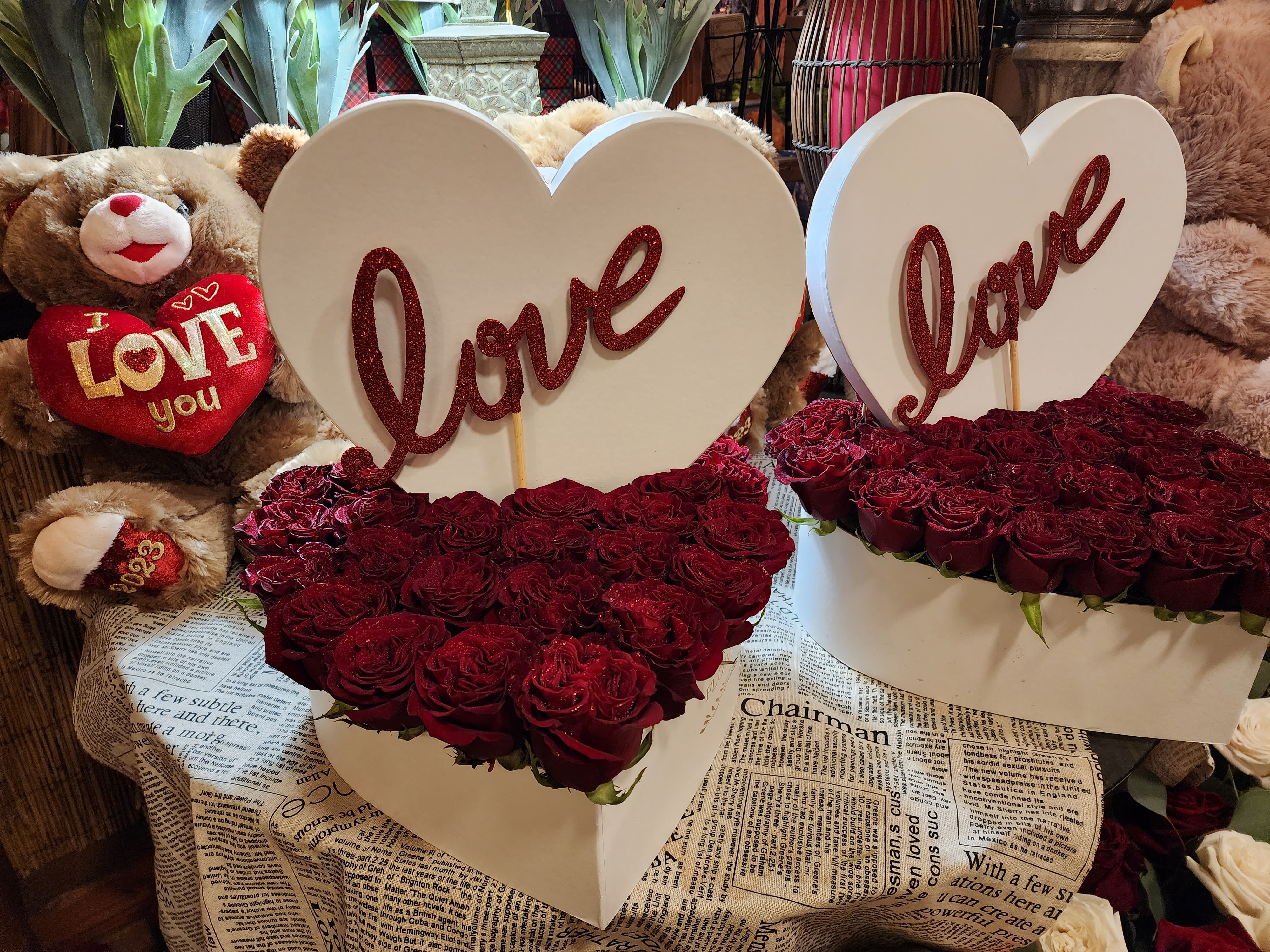 Heart-shaped rose arrangements with "love" signs and teddy bears