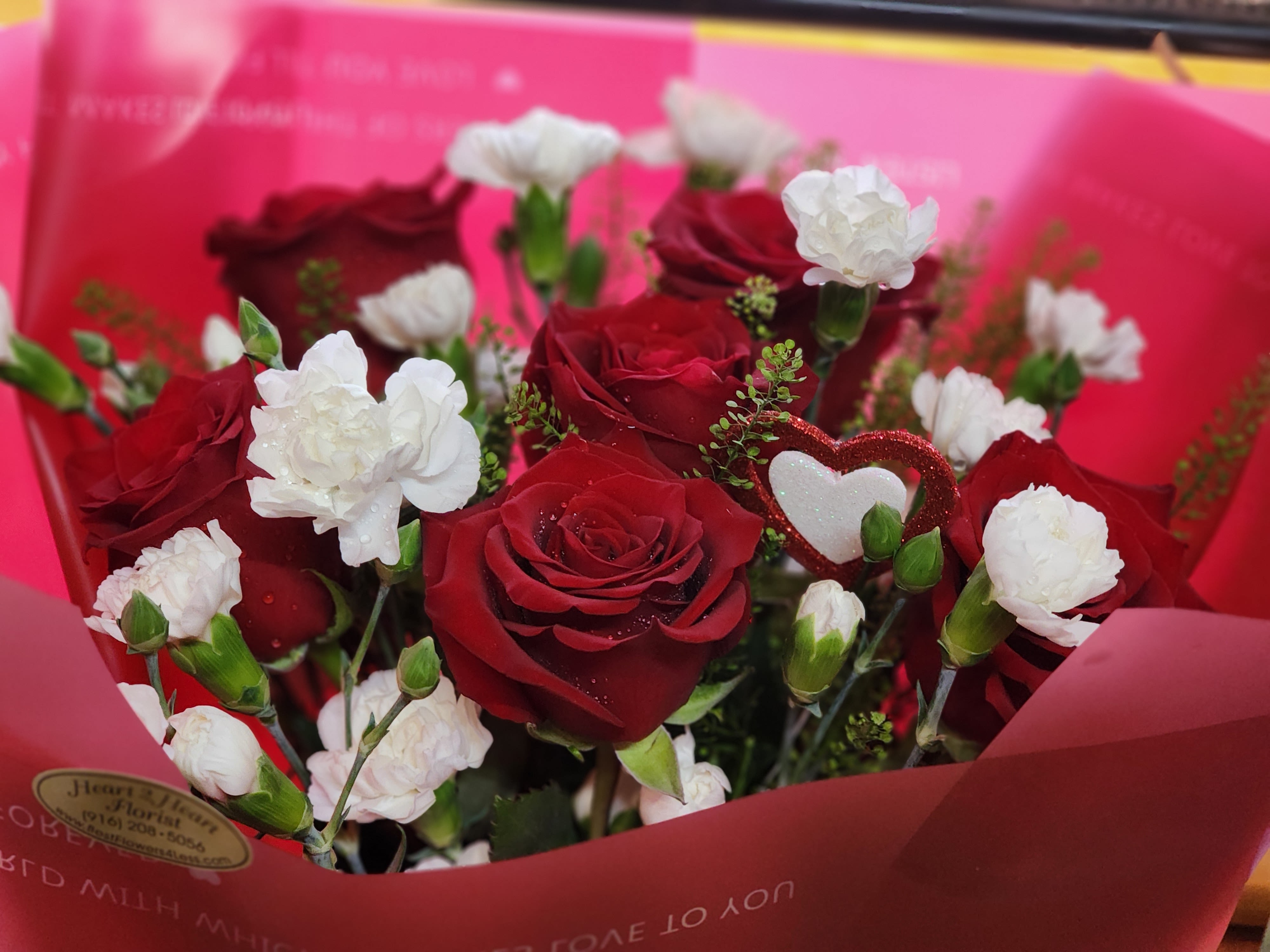 Bouquet of red roses and white carnations in pink wrapping