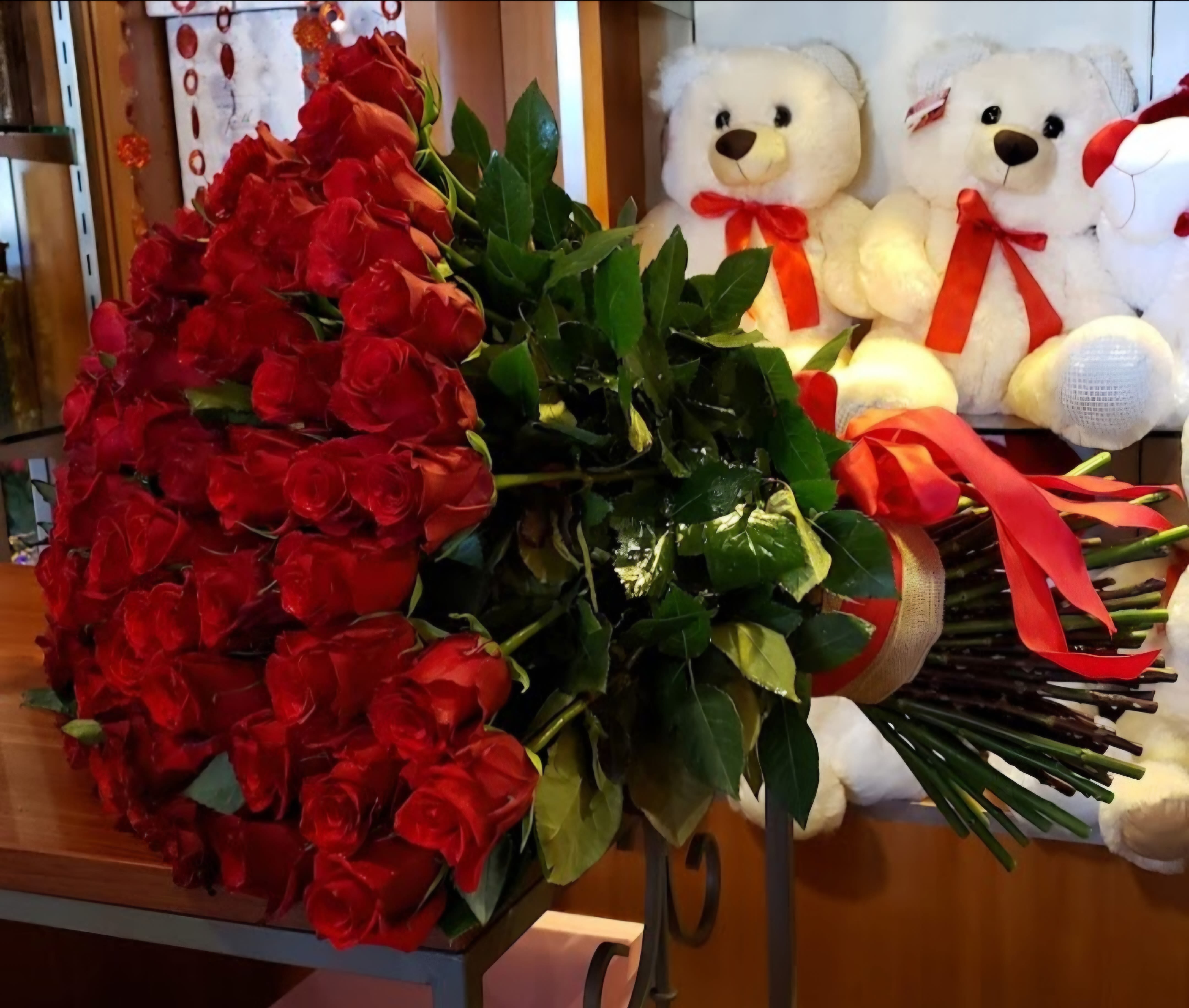 Large bouquet of red roses with teddy bears in the background