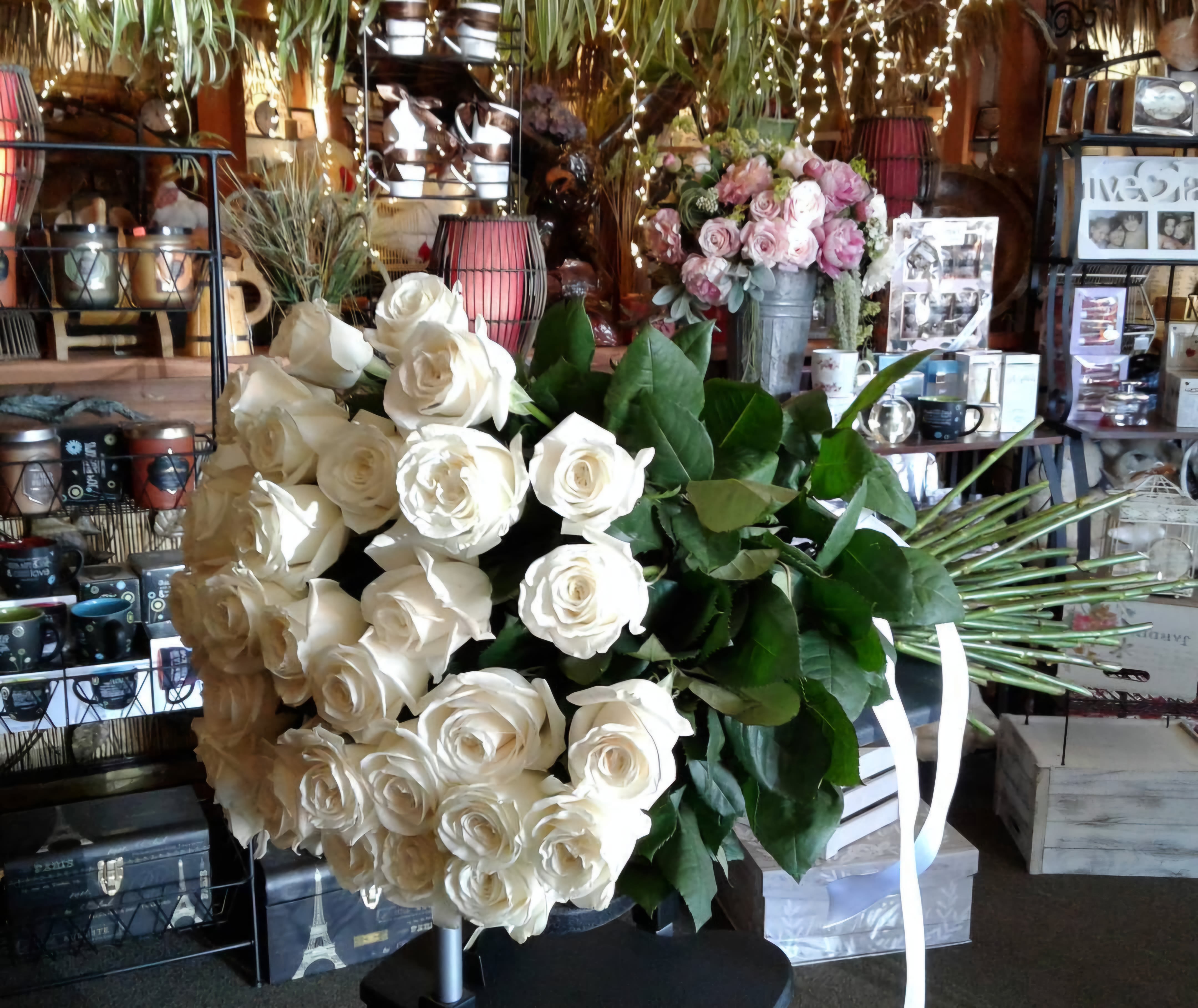 Large bouquet of white roses with green leaves and white ribbon