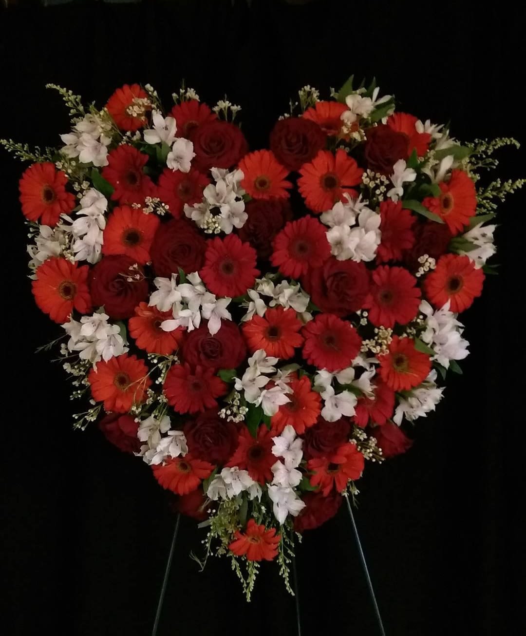 Heart-shaped floral arrangement with red and white flowers on a stand