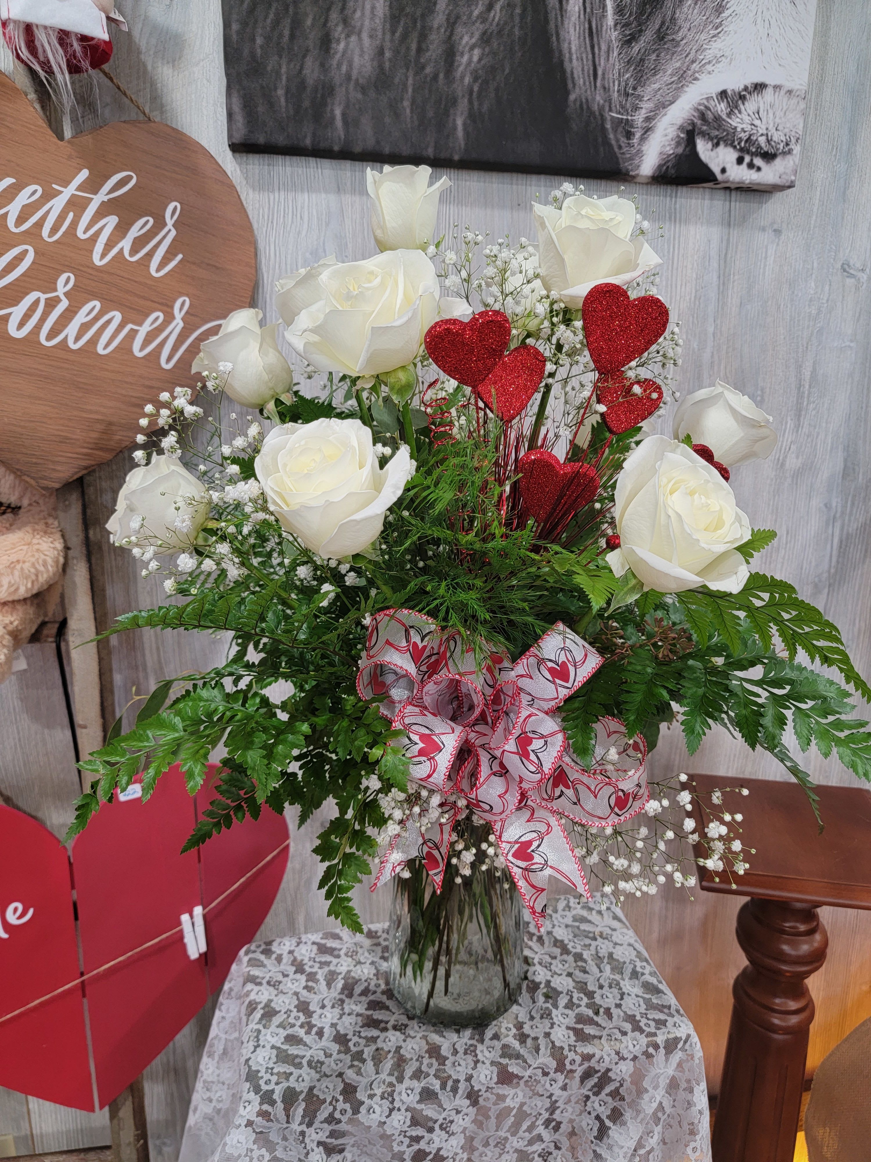 White Dozen Roses - A dozen white roses arranged in a vase. Full with greenery and additional filler flowers. 