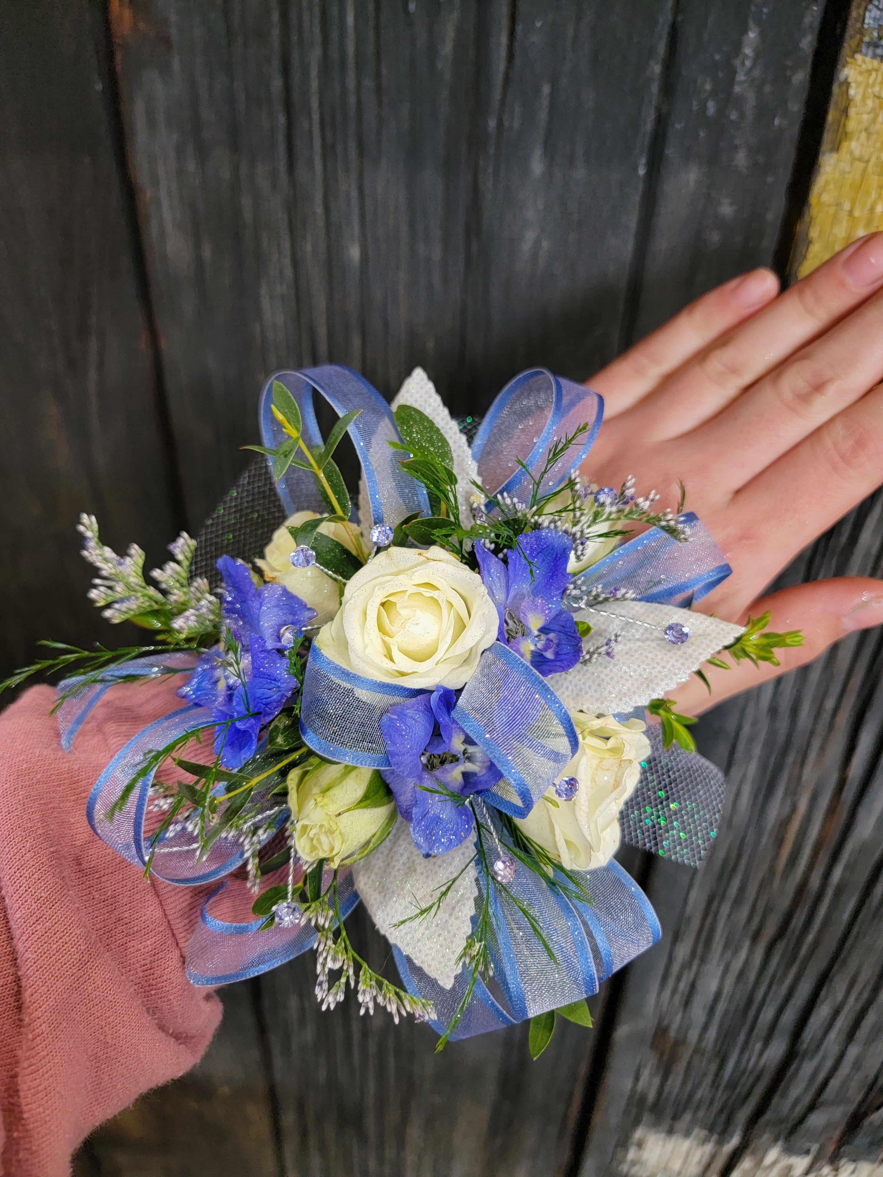 Blue Corsage  - A beautiful corsage with blue tones made with your choice of flowers.  Options include: roses, mini carnations, alstromeria, daisies, or cushion mums  Please include preferred flower type, shade of blue, and accent colors in description of order! Or simply reply with designer choice!   Deluxe pricing includes more flowers 