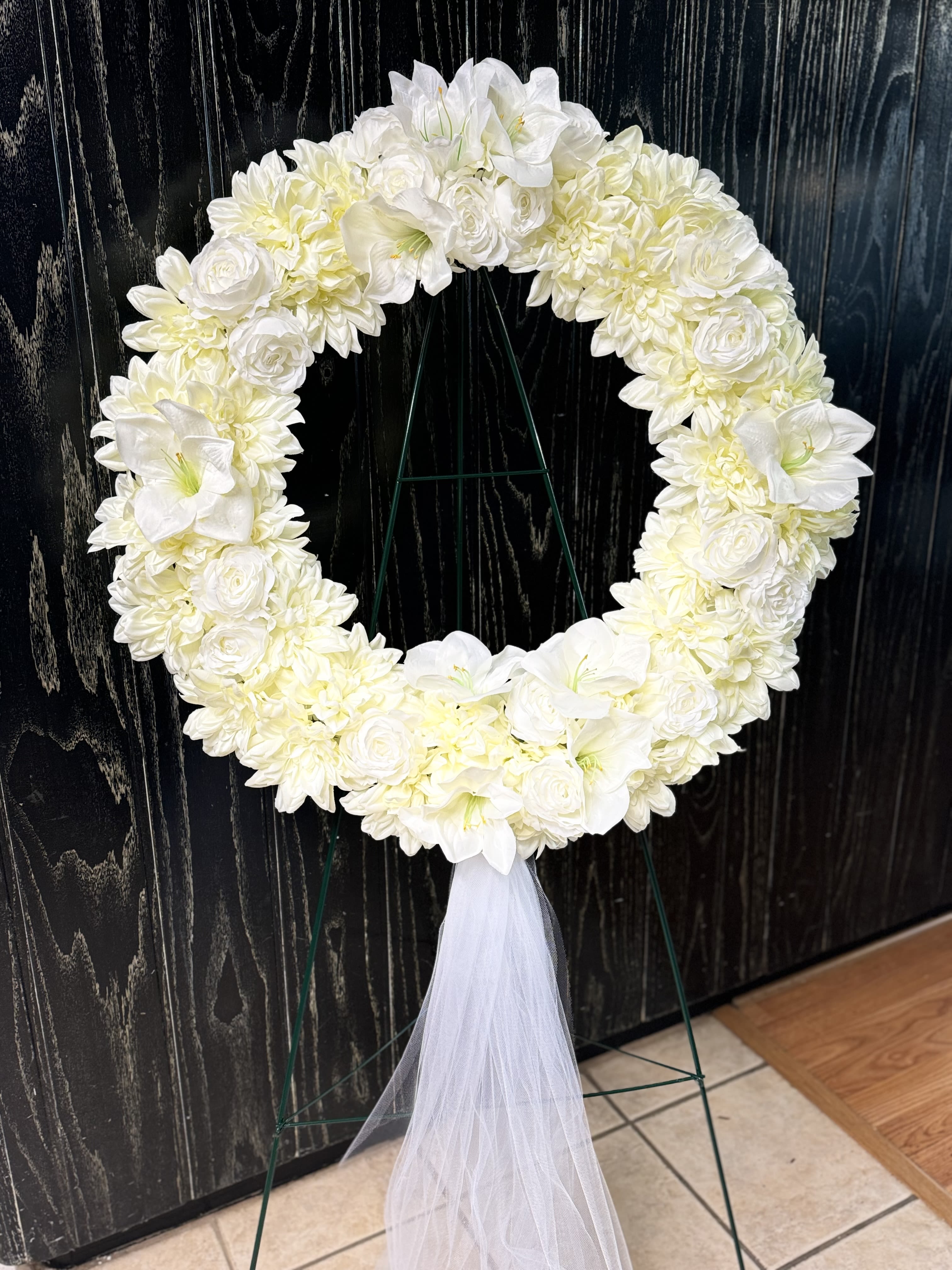 White floral wreath on a stand with a tulle ribbon
