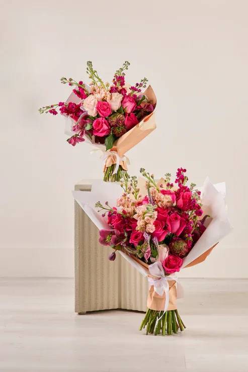 Two pink and peach flower bouquets wrapped in paper