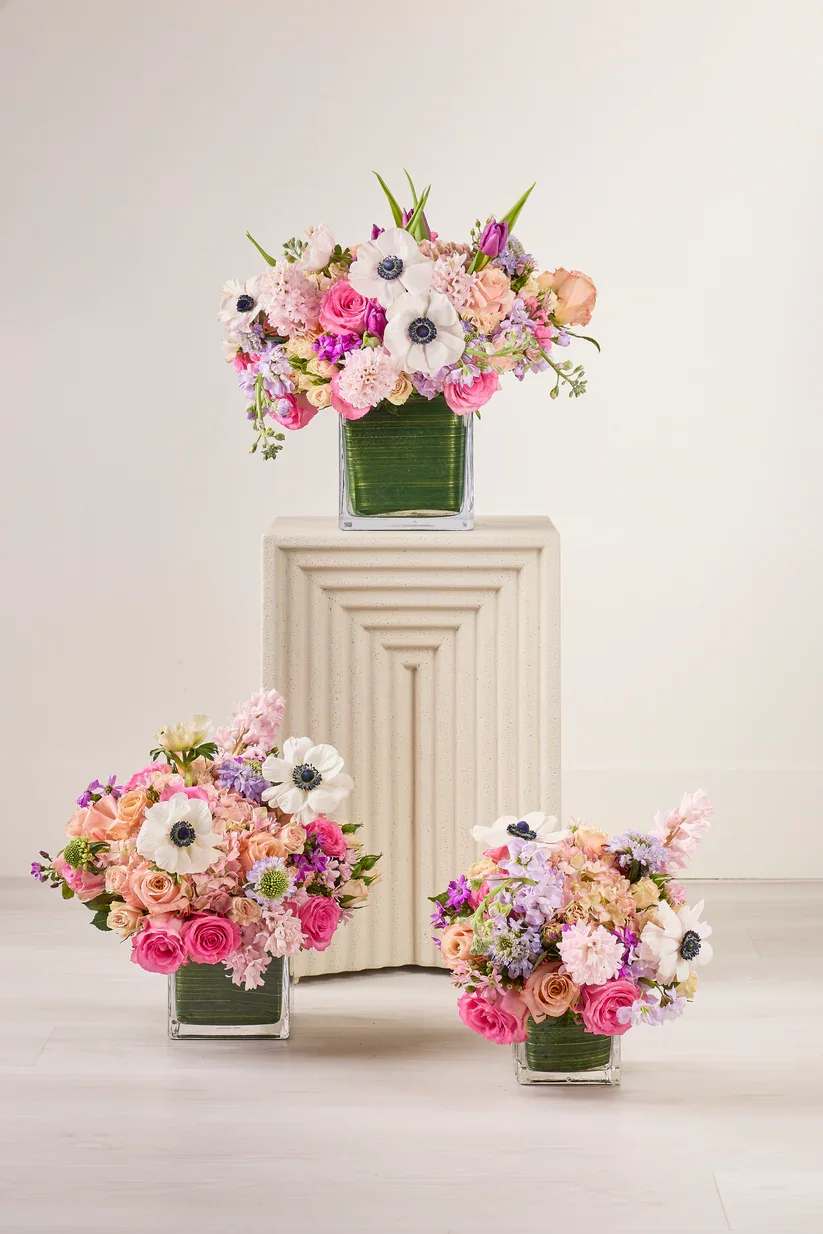 Three pastel floral arrangements in square glass vases