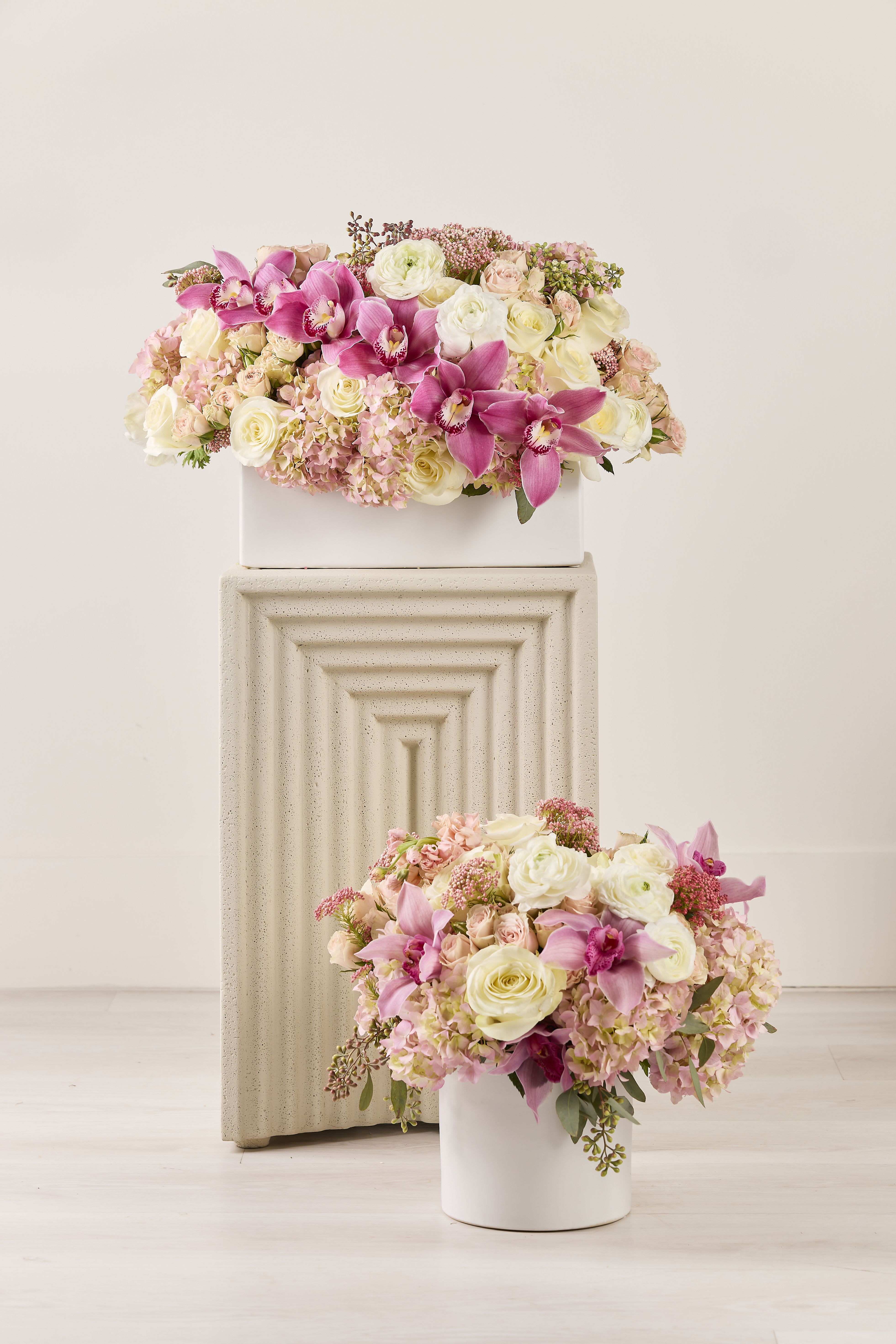 Pink and white floral arrangements in white containers