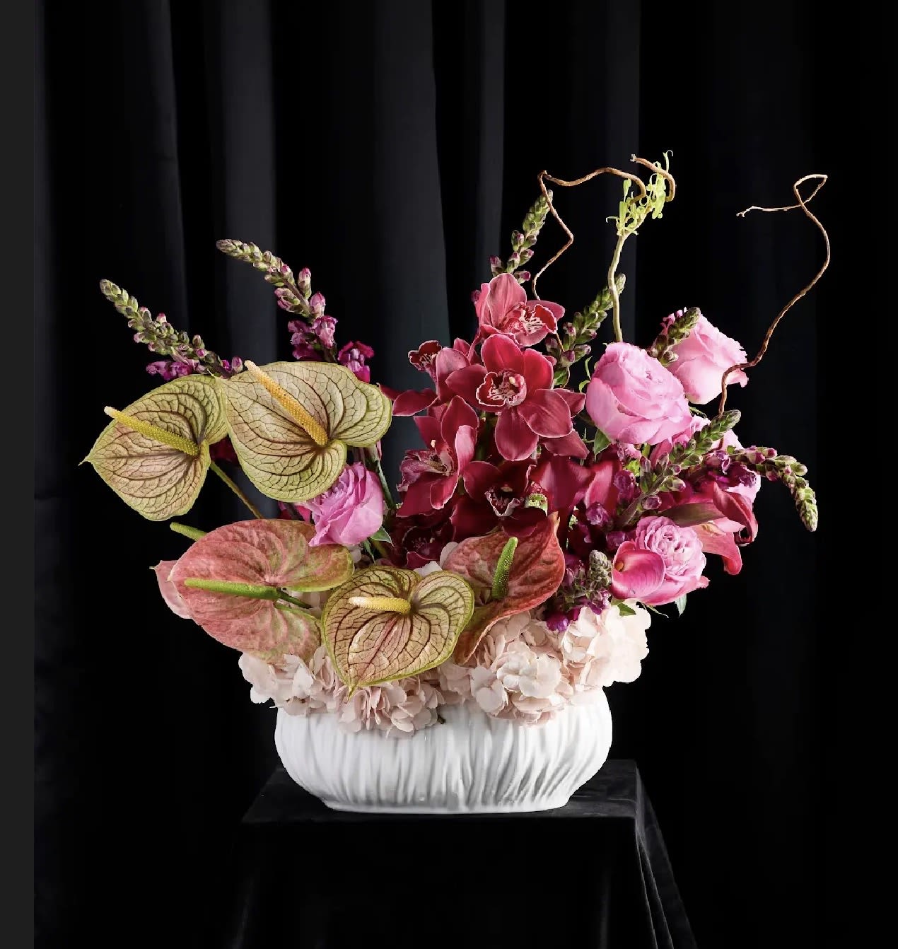 Pink and burgundy floral arrangement in a white vase