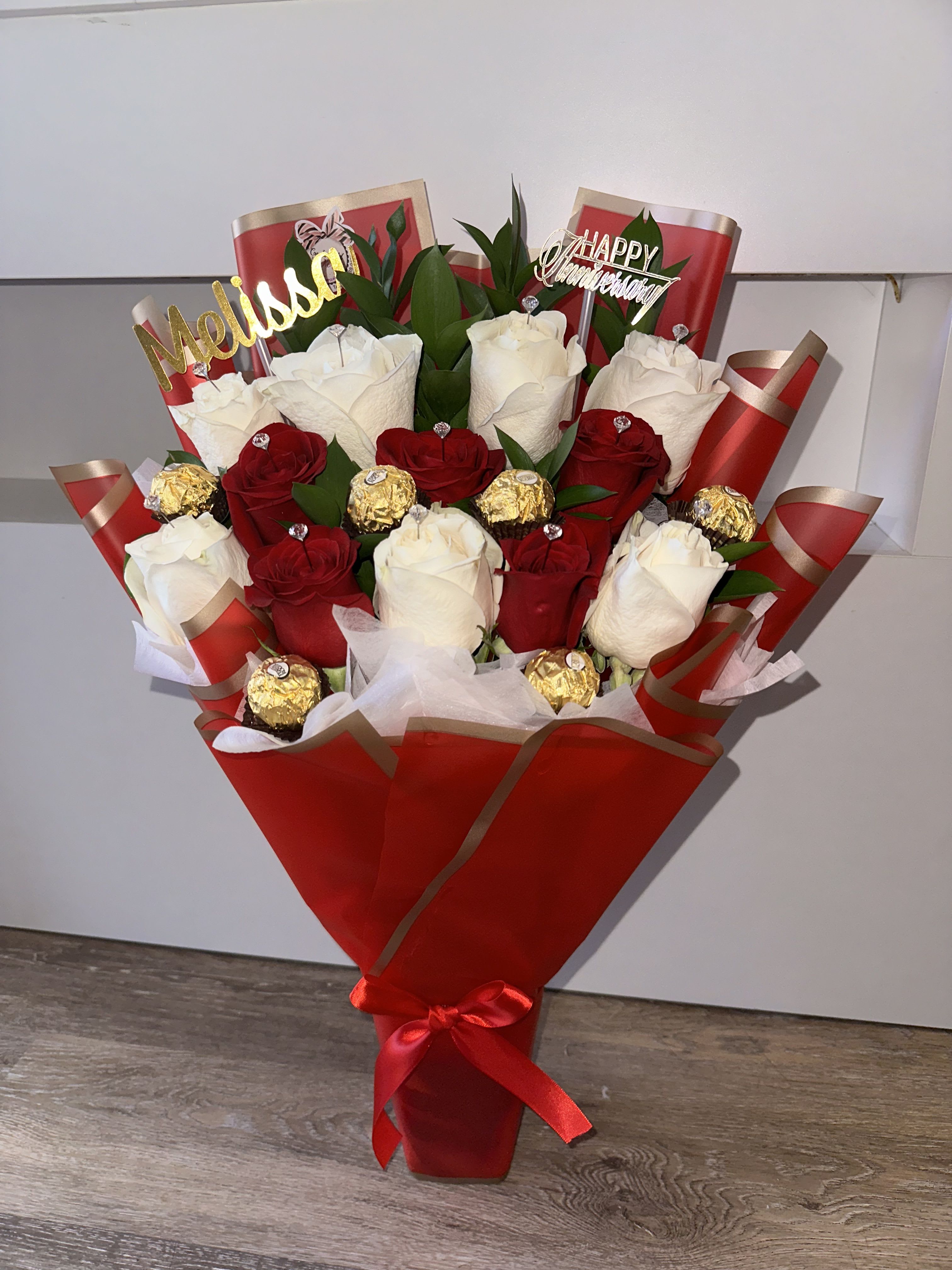 Bouquet of red and white roses with chocolates in red wrapping