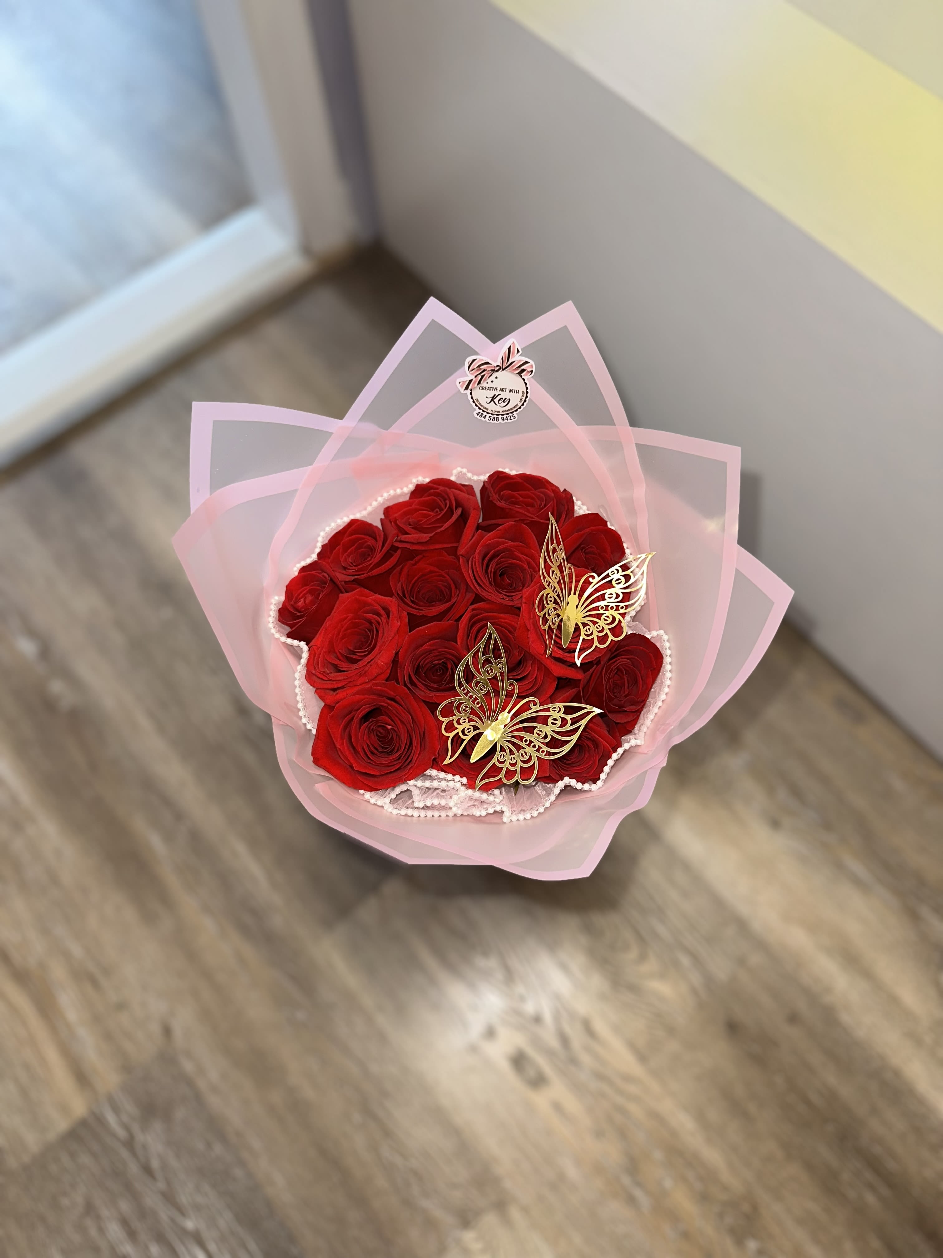 Bouquet of red roses wrapped in pink paper with butterfly decorations