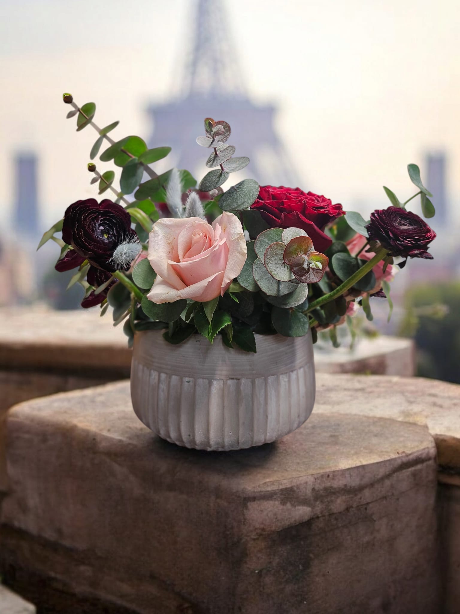 Pink and red roses in a ribbed white vase with eucalyptus