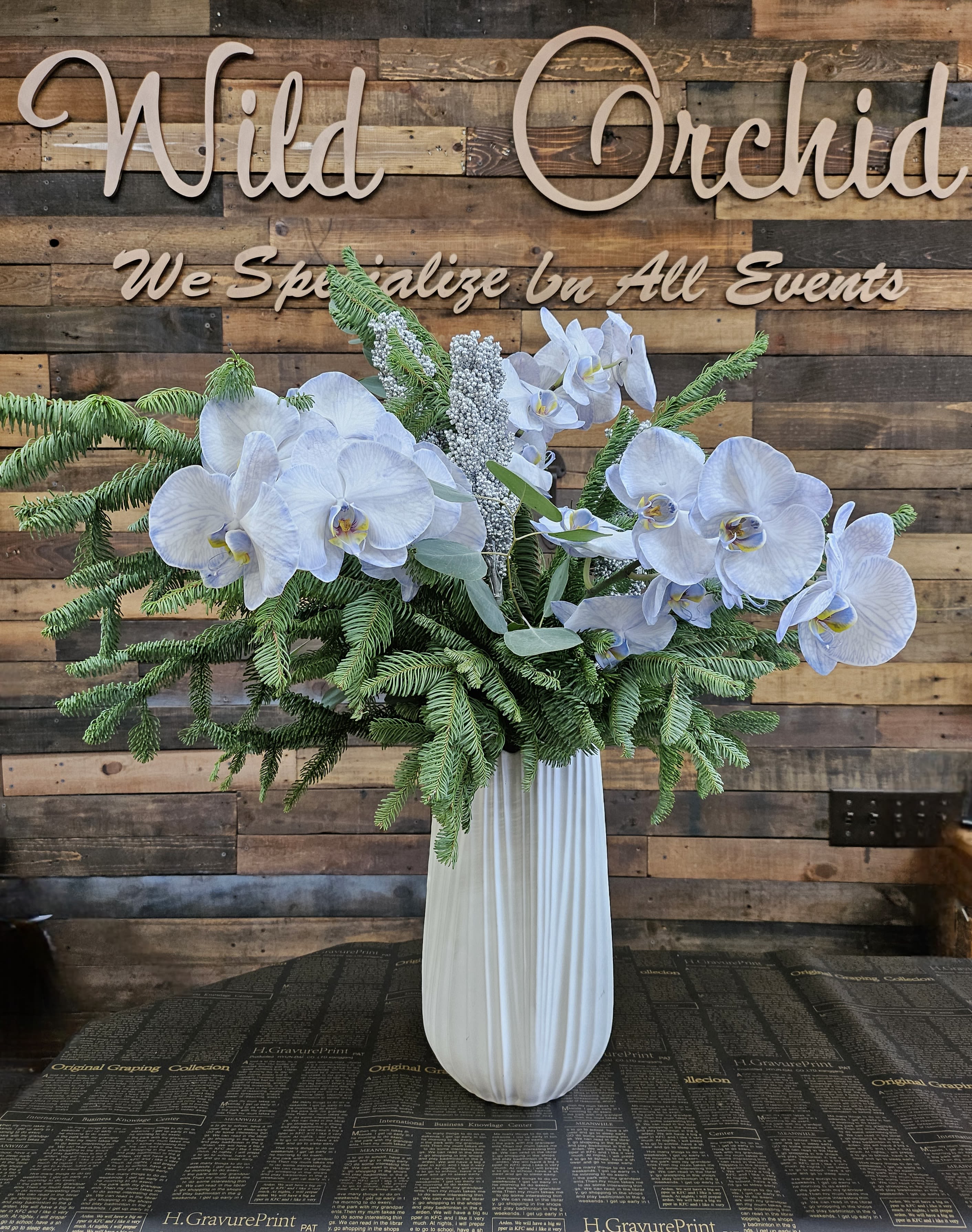 White orchid arrangement in a tall ribbed vase