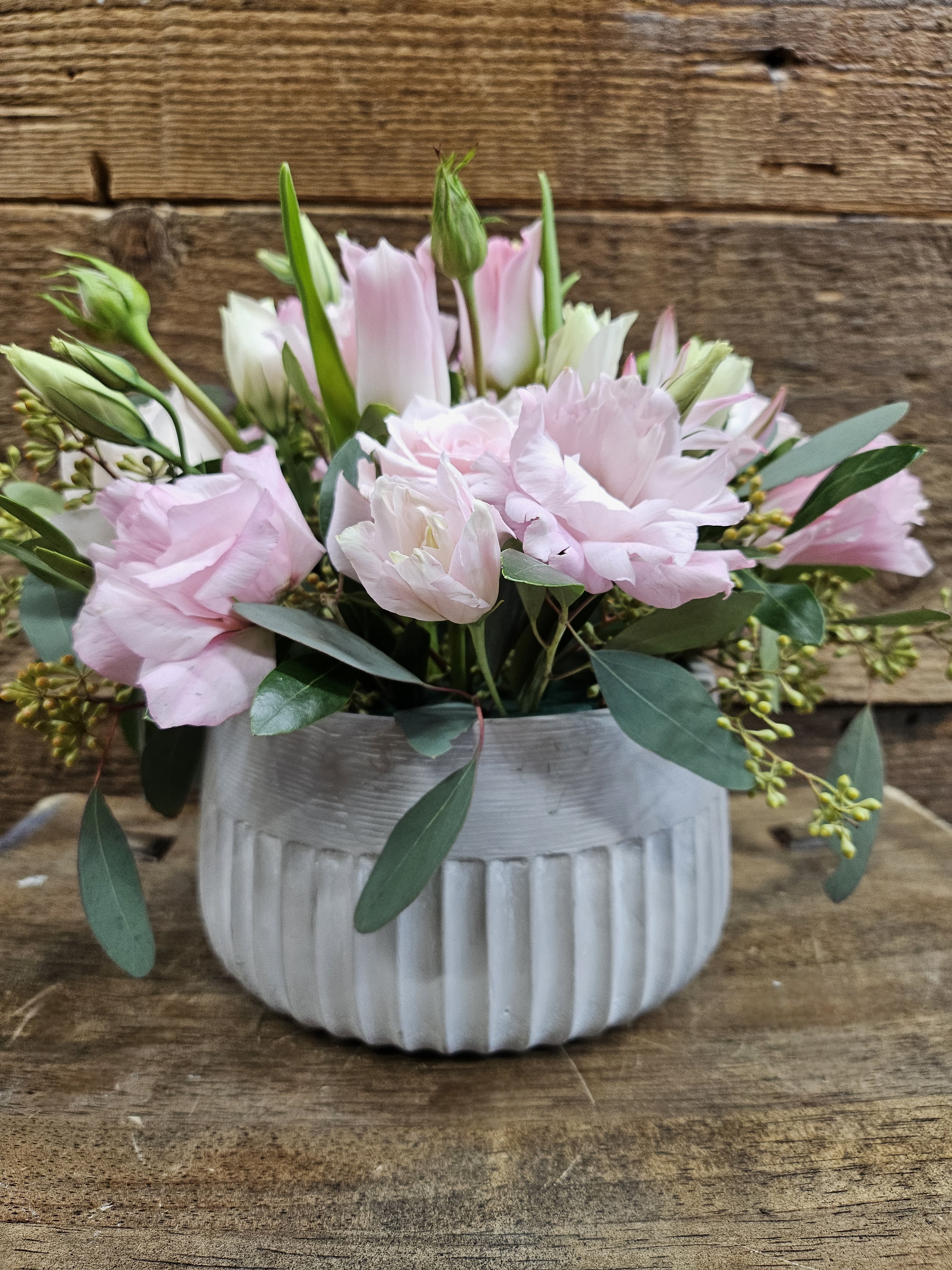 Pink and white flowers arranged in a ribbed white vase