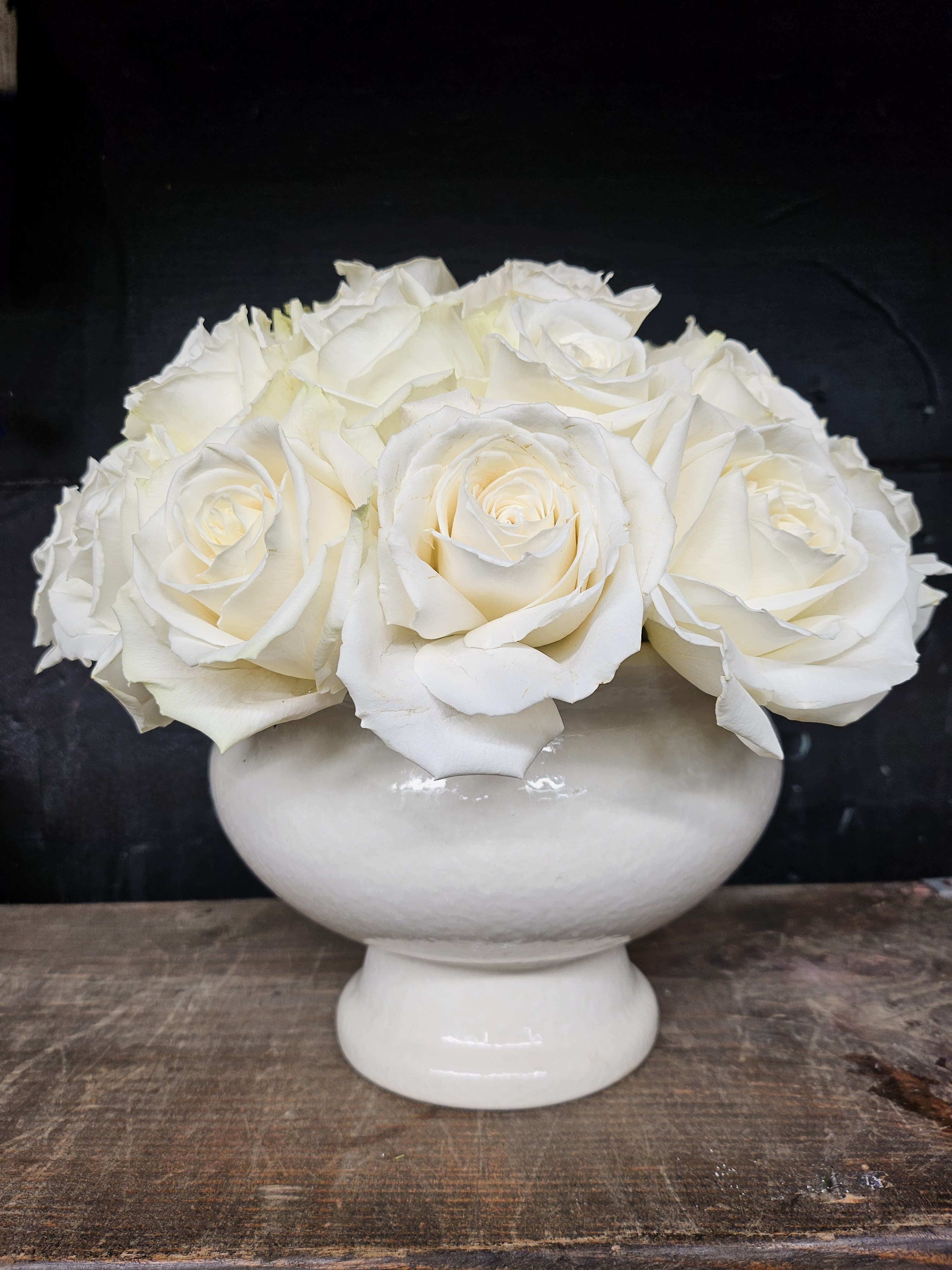 White roses arranged in a white pedestal vase