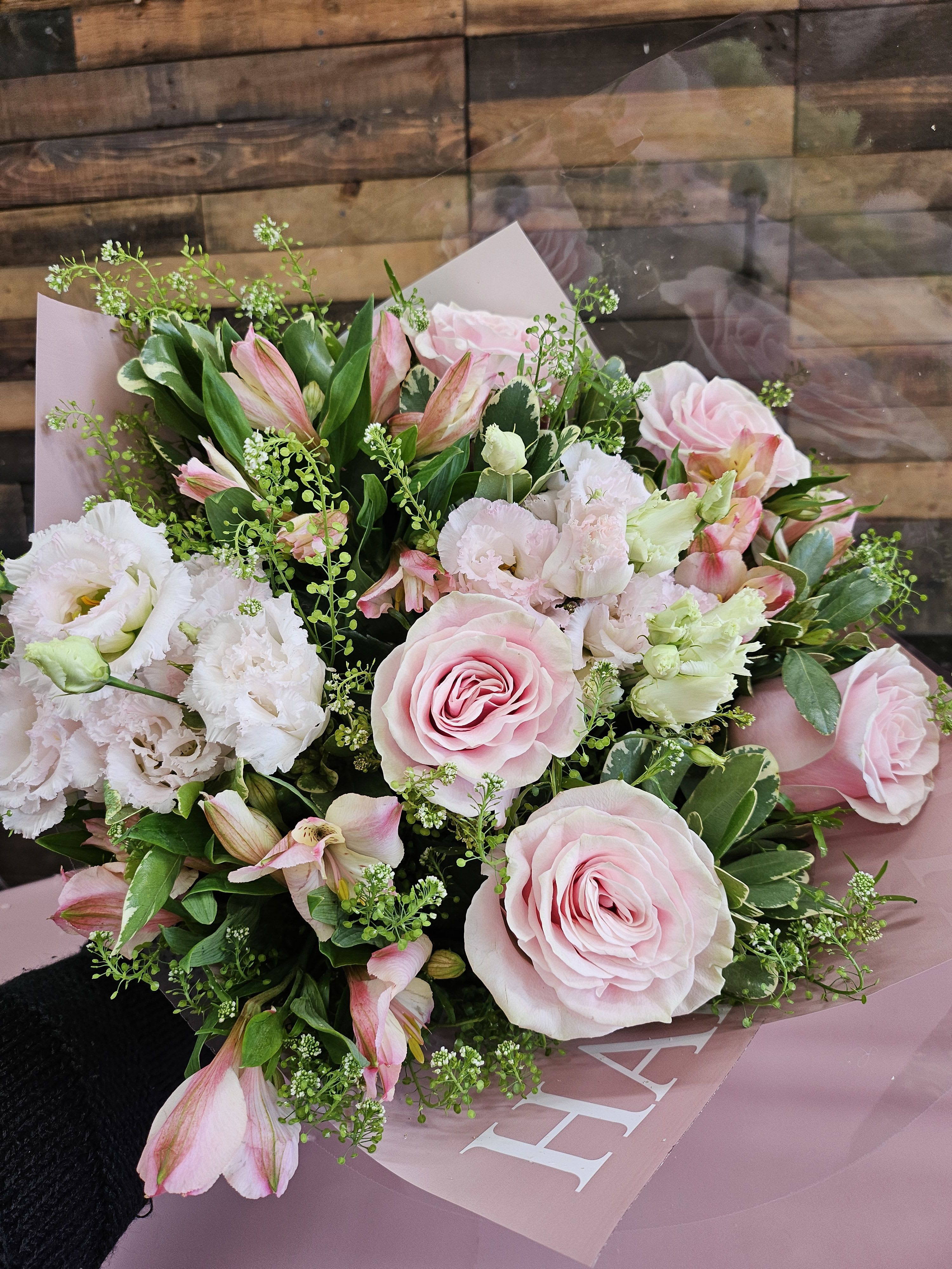 Pink roses and white blooms in a hand-tied bouquet with pink wrap