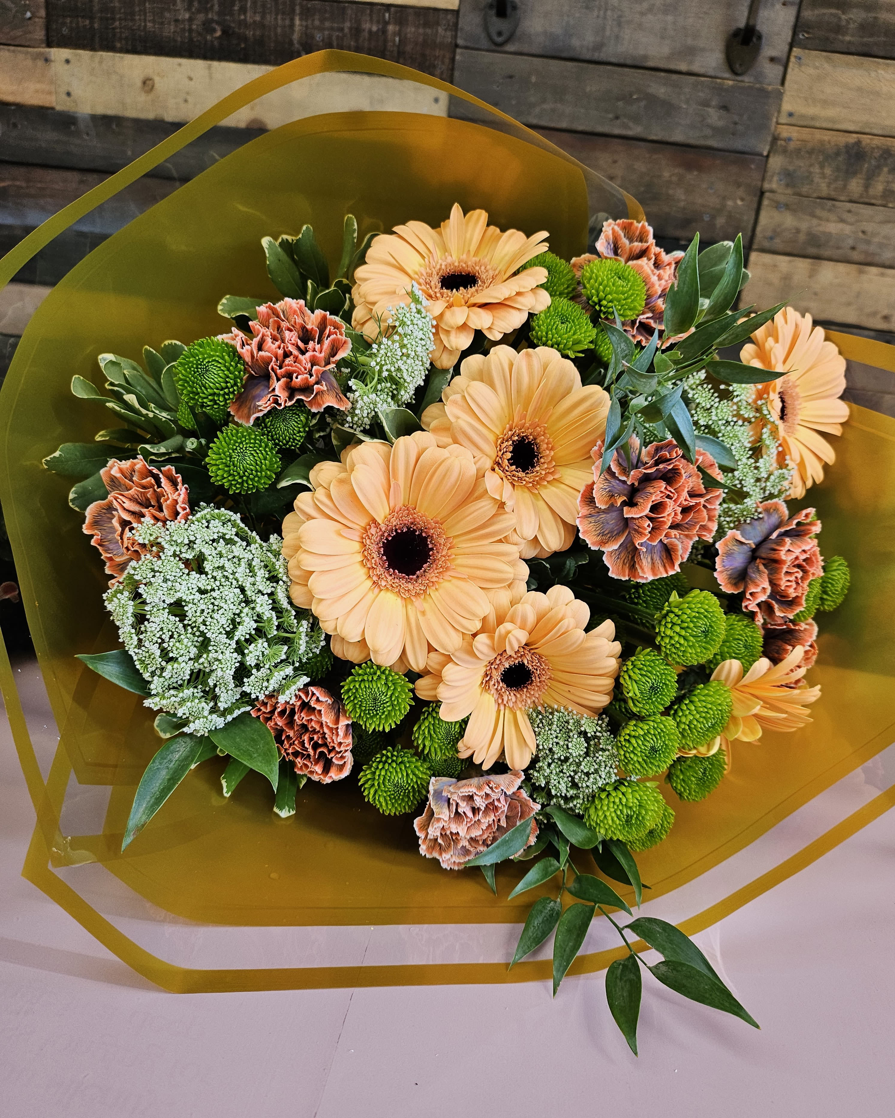 Bouquet of peach gerbera daisies and green button mums with orange carnations