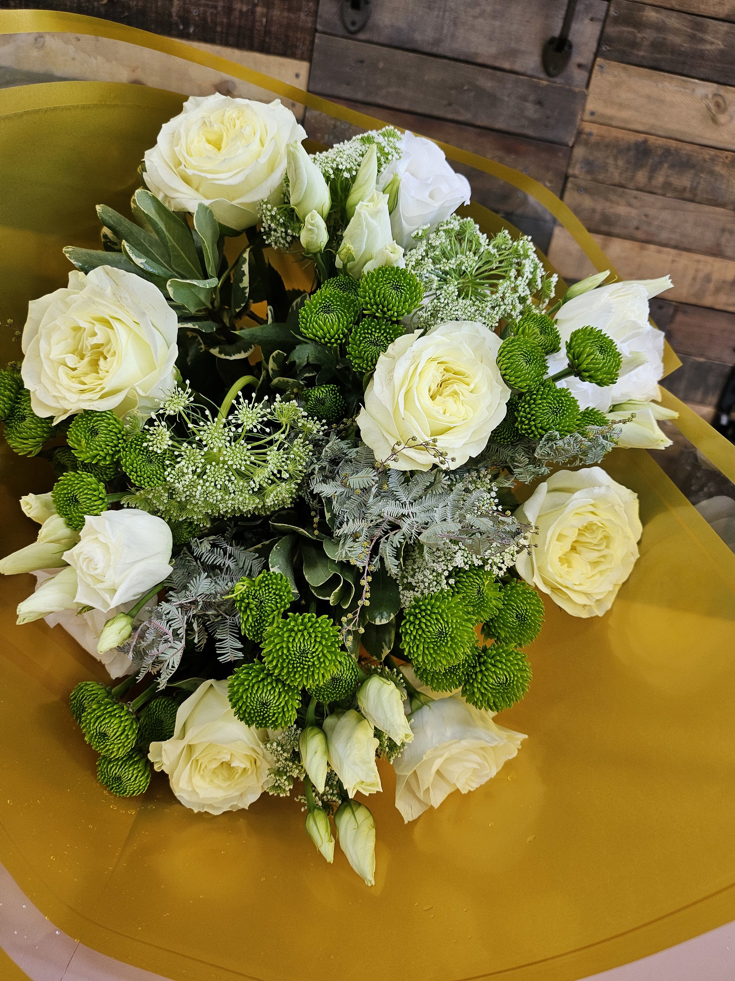 Bouquet of white roses and green button mums wrapped in gold paper