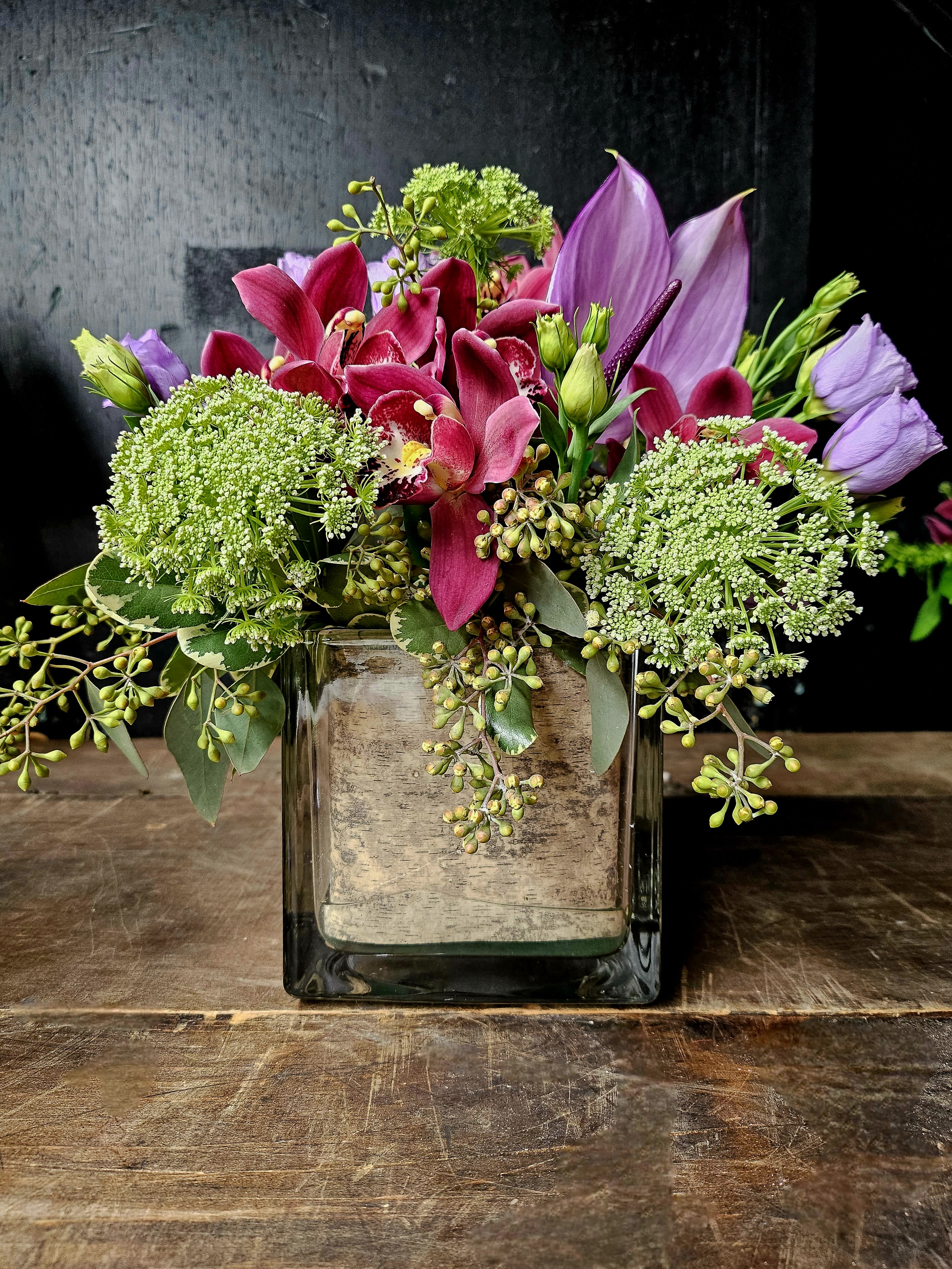 Pink and purple floral arrangement in a square glass vase