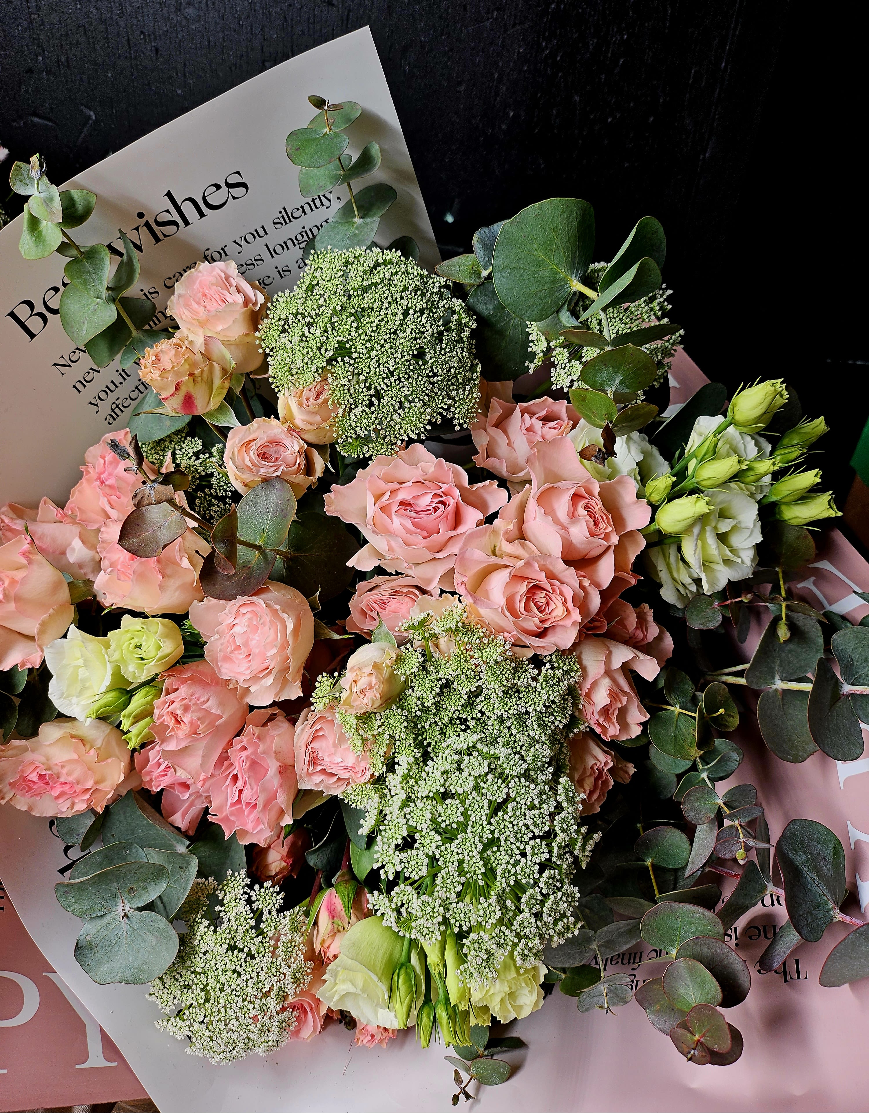 Bouquet of pink roses and white blooms with eucalyptus and a card