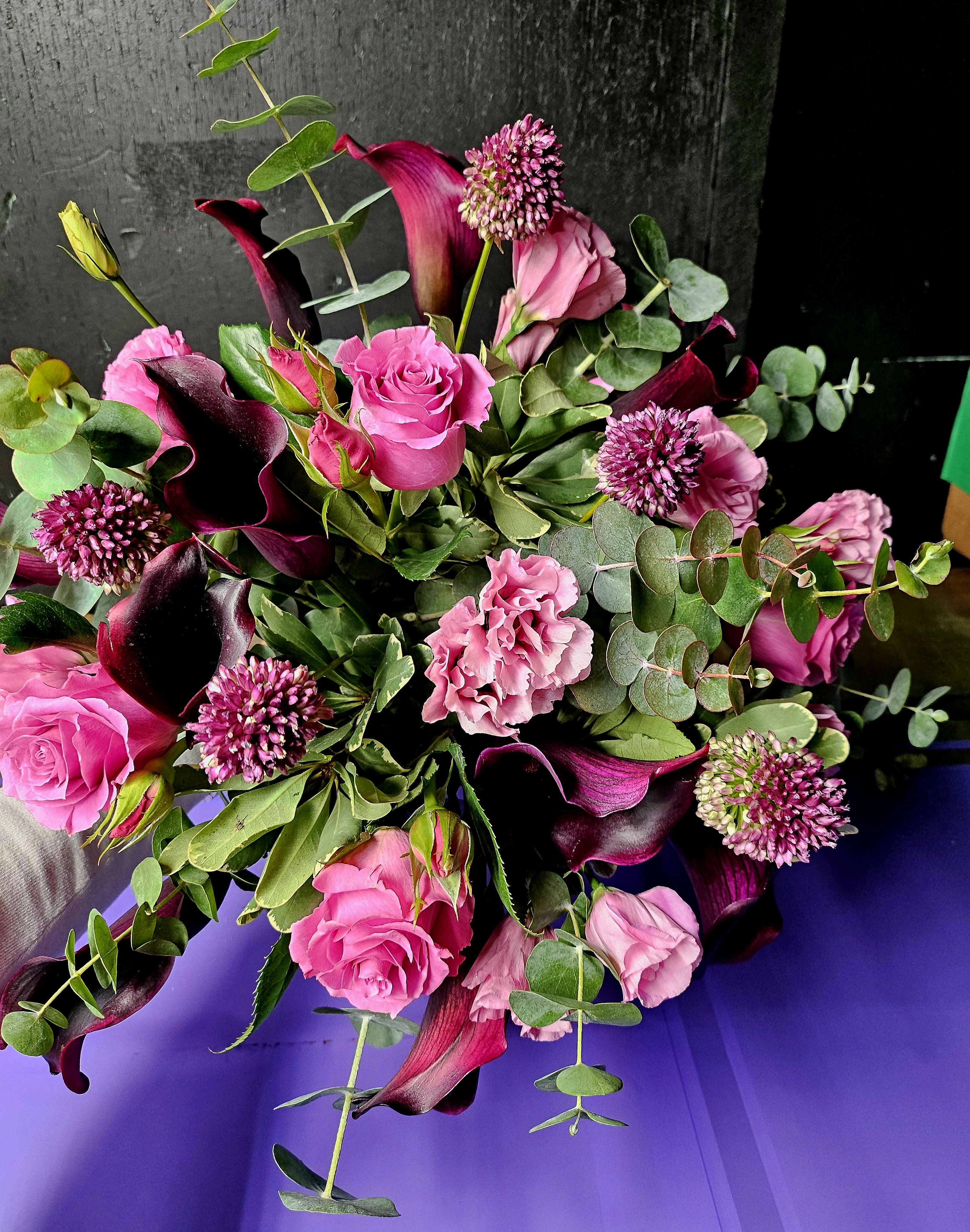 Bouquet of pink roses, calla lilies, and purple blooms with eucalyptus