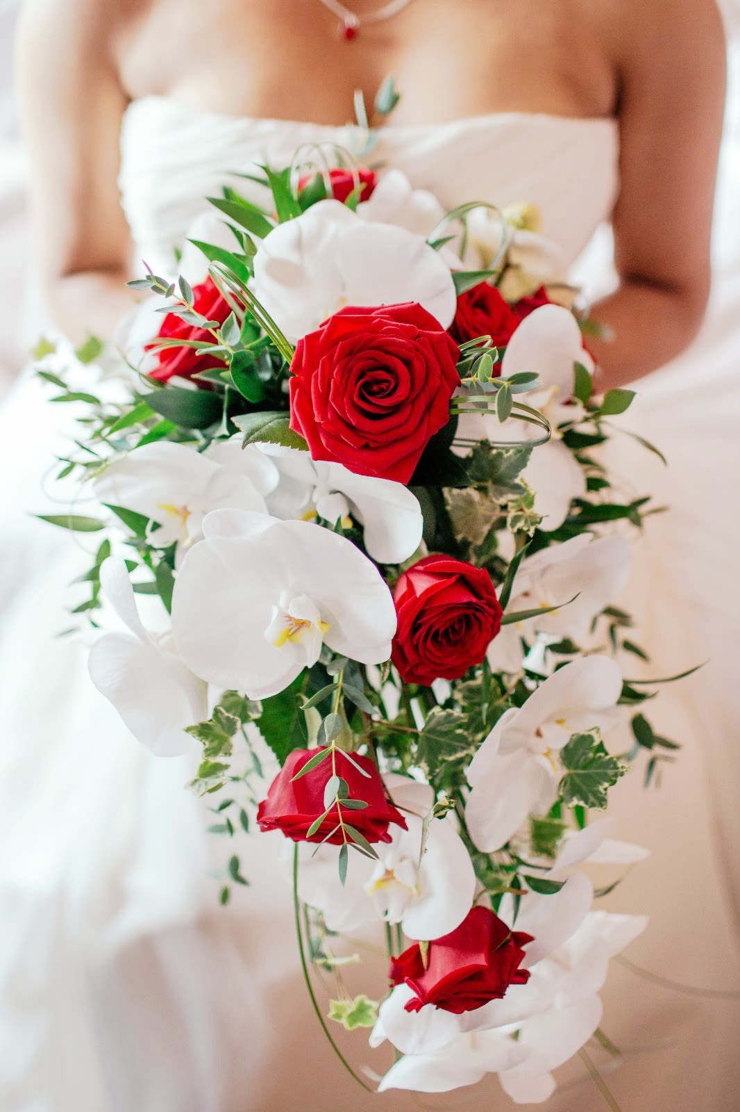 Bride holding a bouquet of red roses and white orchids