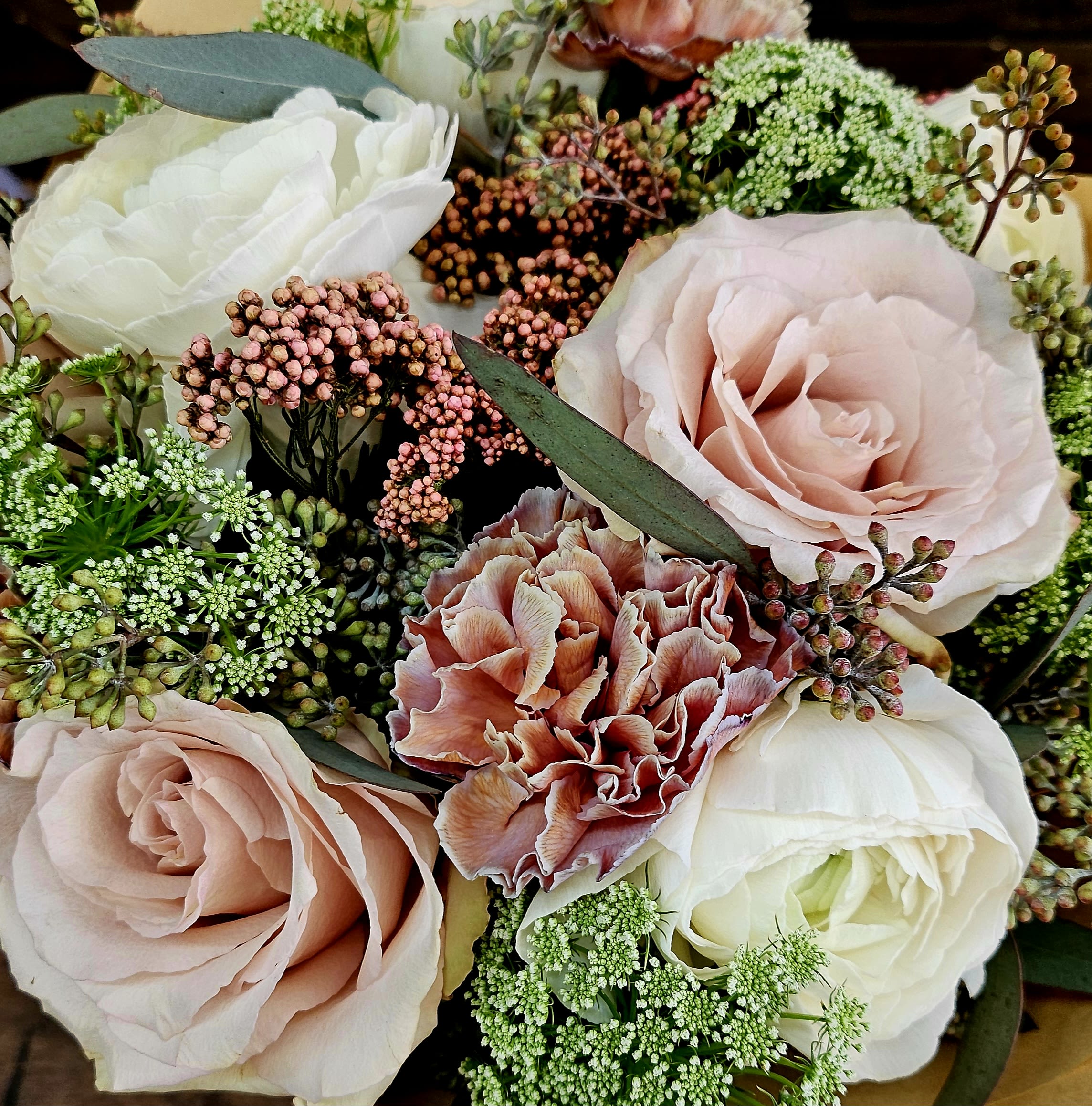Close-up bouquet of blush roses, white blooms, and pink carnations