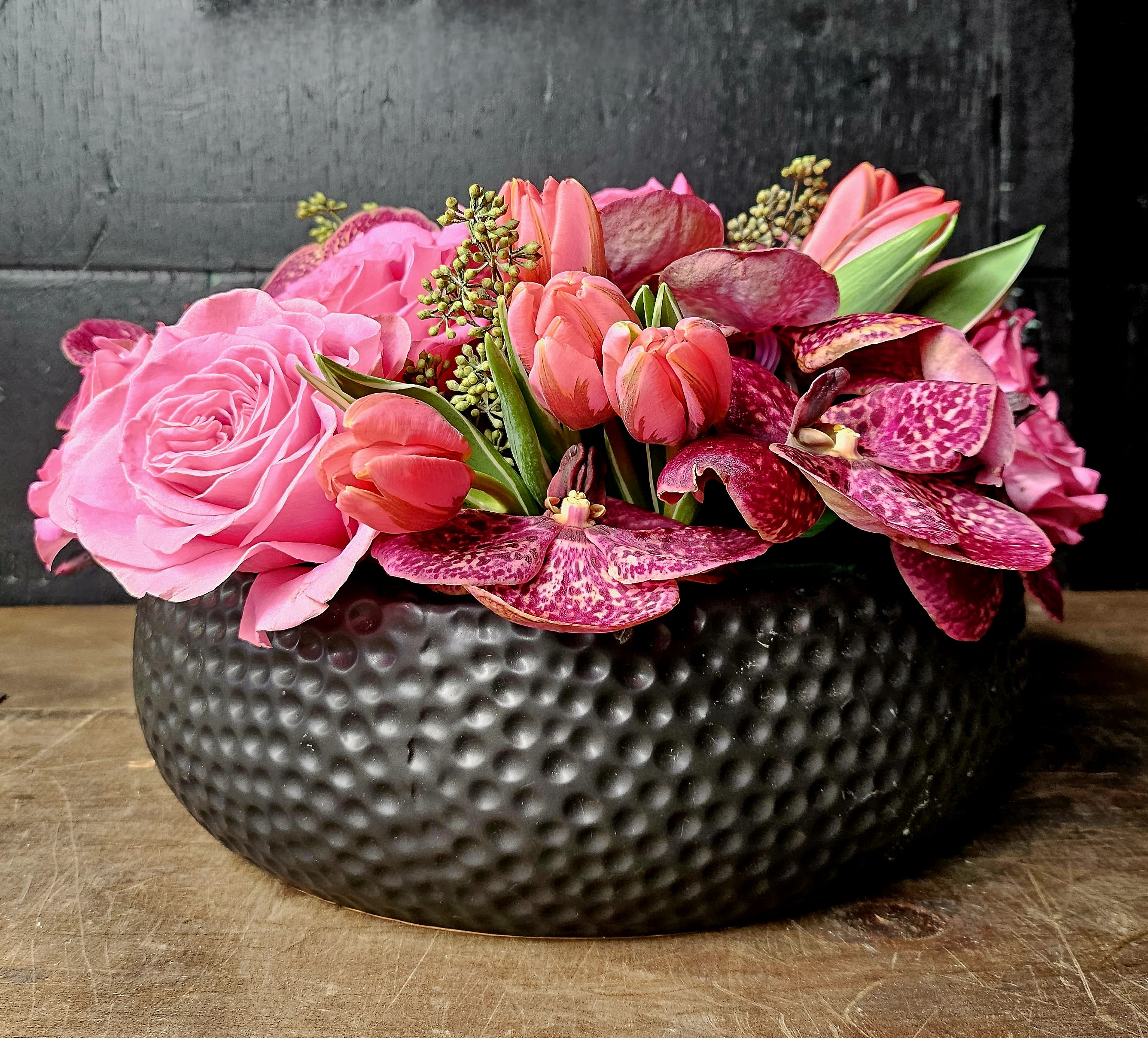 Pink roses and tulips arranged in a black textured bowl